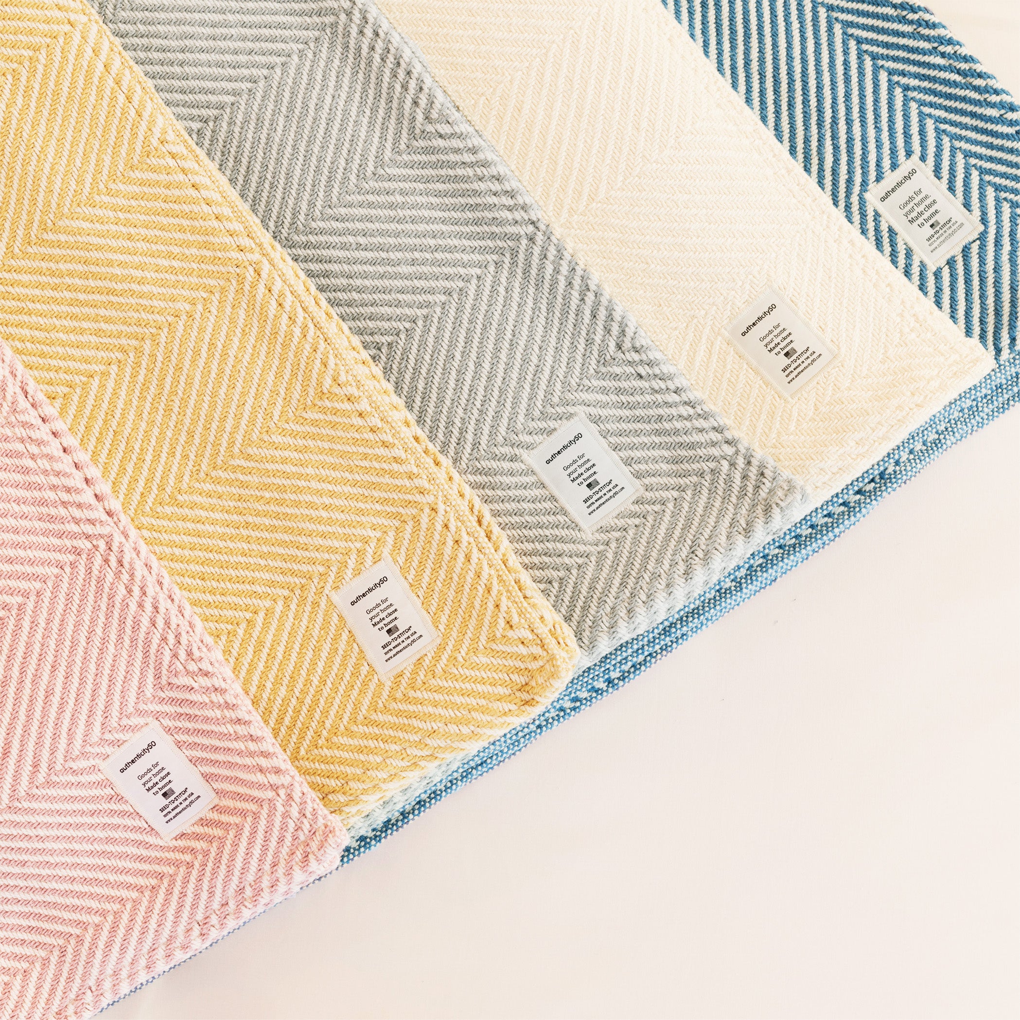 Five Heritage Blankets (one for each available color) folded and laid out in a line.