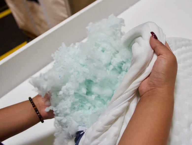 Worker opening an A50 Travel Pillow outer cover to reveal the clean CertiPUR-US foam stuffed inside.