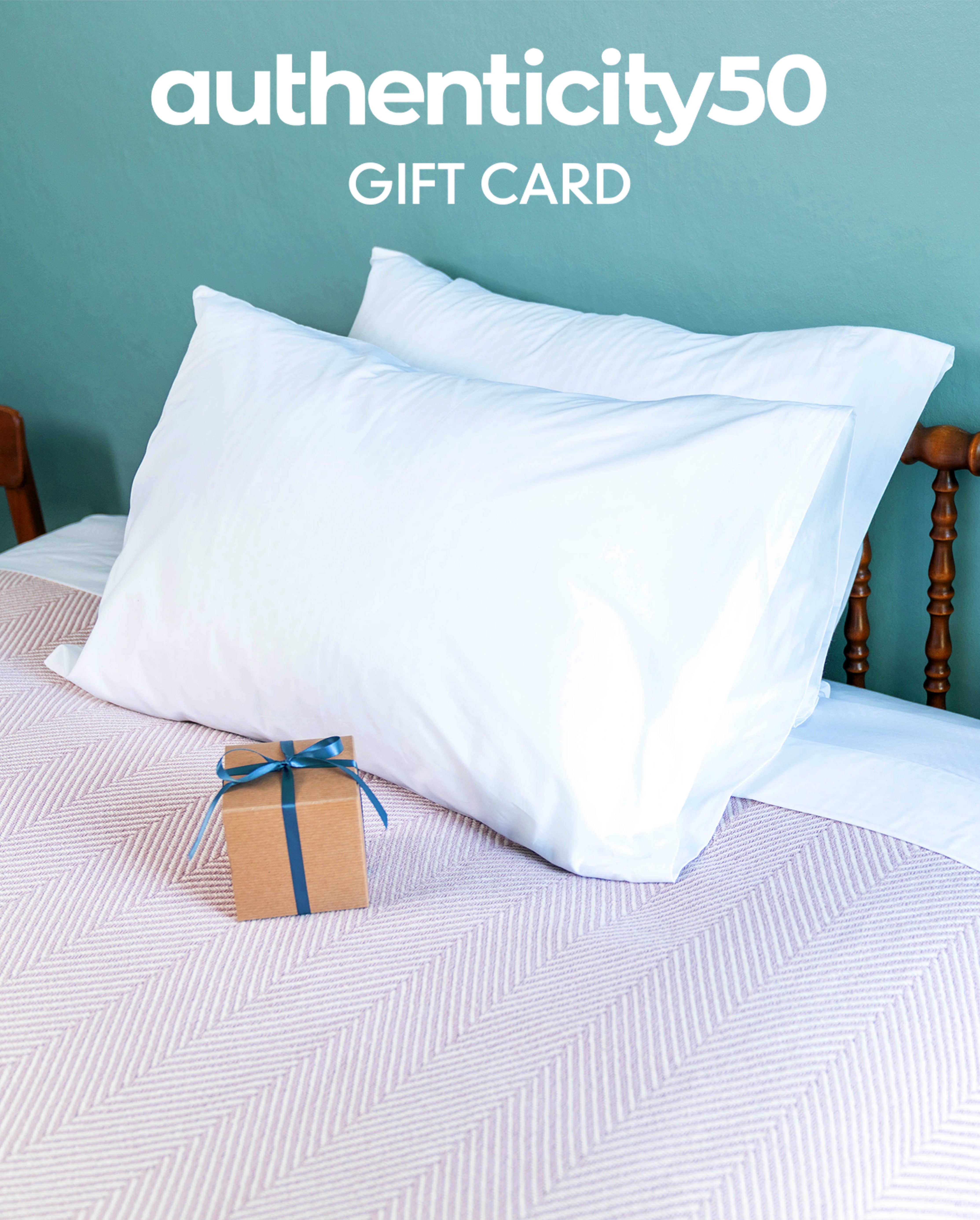 Wrapped gift sitting on a bed made with misc. A50 products (Envelope Closure Pillowcases, Custom Comfort Pillows, Heritage American Sheets, and a Heritage Blanket) with the overlaying text: Authenticity50 Gift Card.