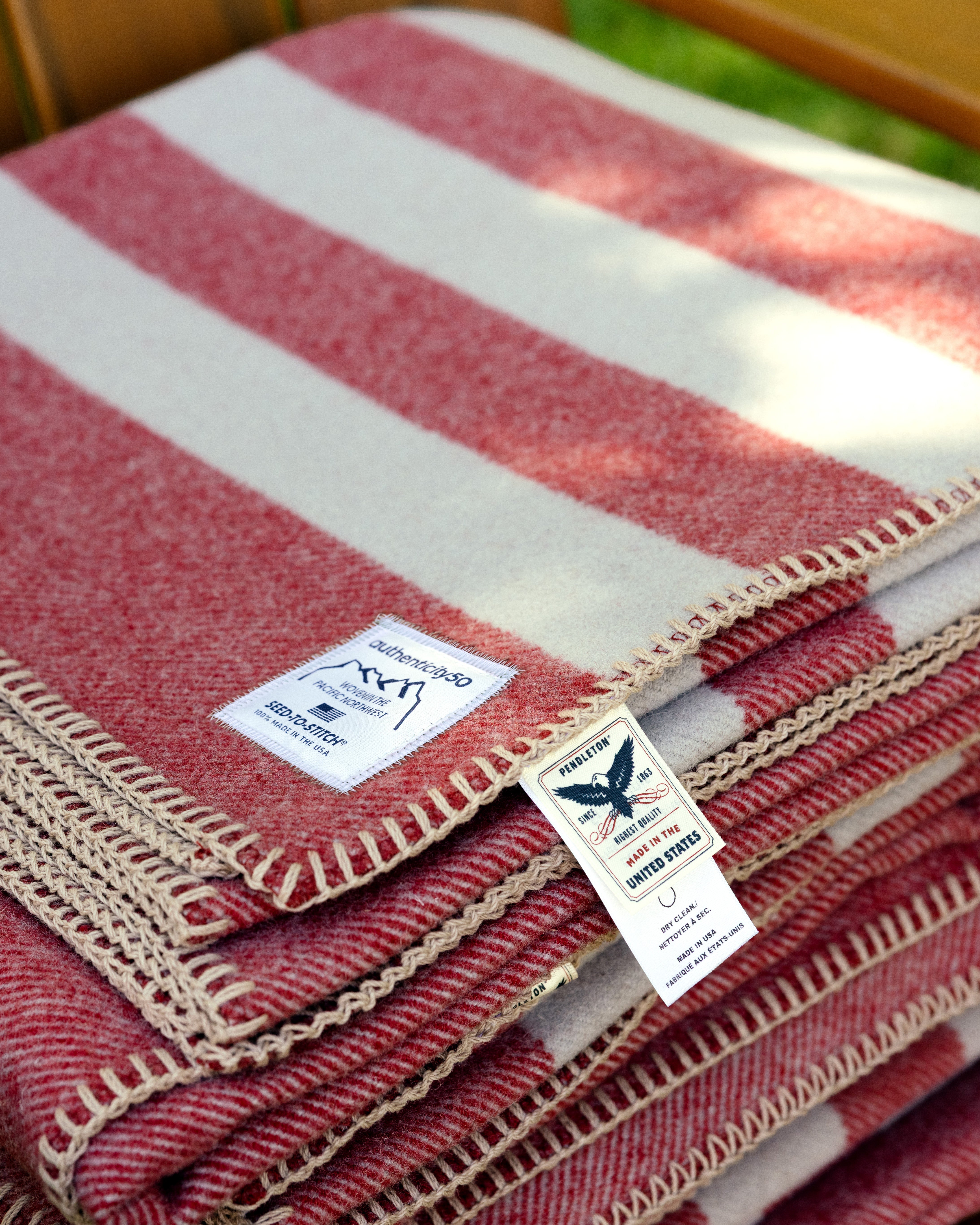Northwest Wool Throw folded and sitting on a chair. The custom Authenticity50 label and Pendleton Woolen Mills® tags are on display.