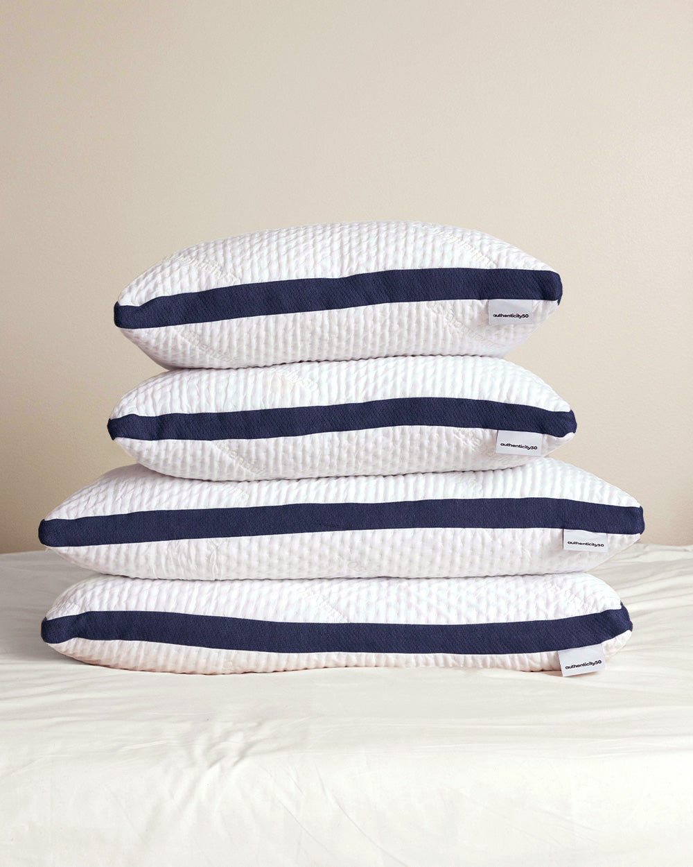 Stack of Custom Comfort Pillows sitting on a bed that's made with Heritage American Sheets.