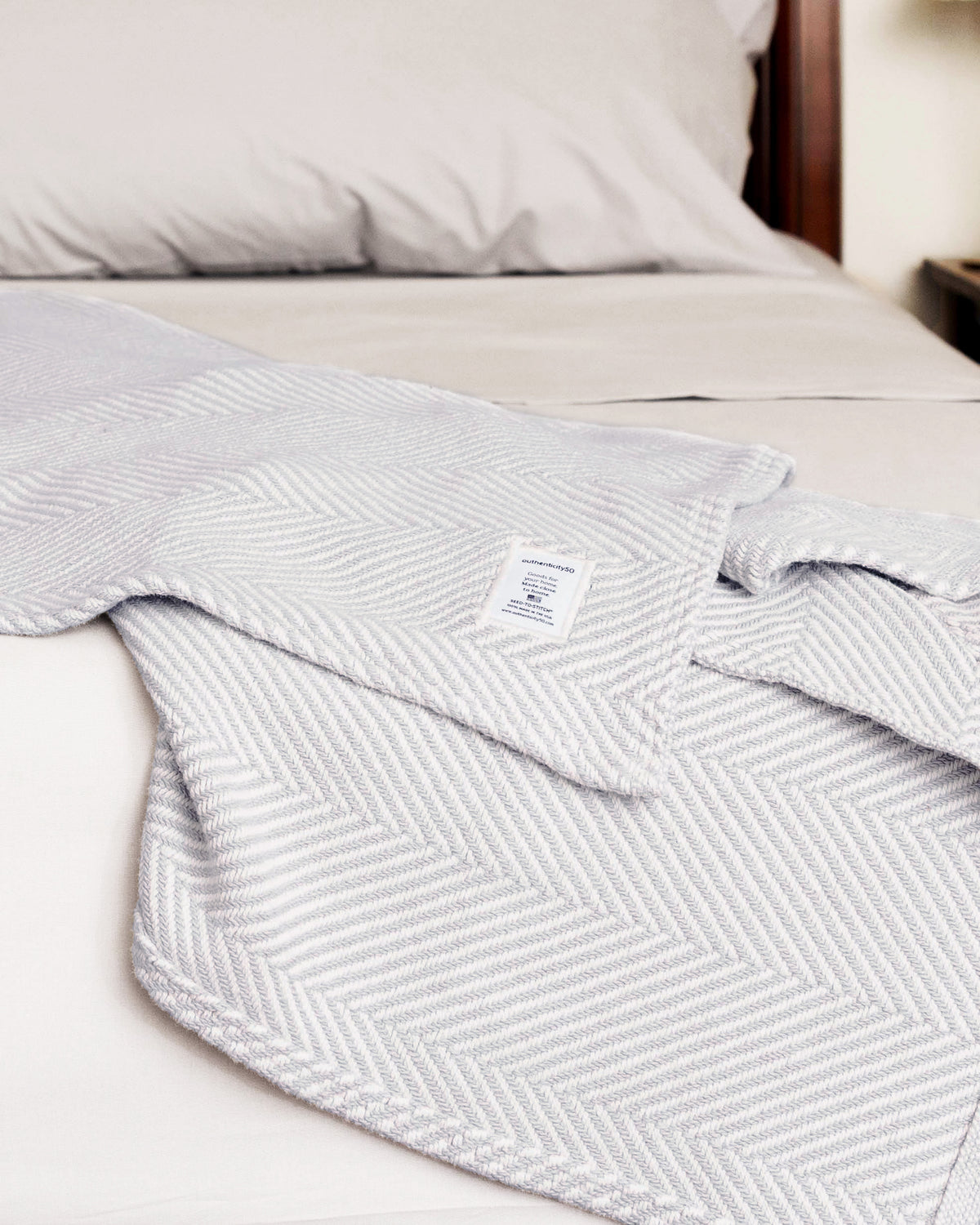 Cascade Gray Heritage Blanket splayed on the edge of a bed.