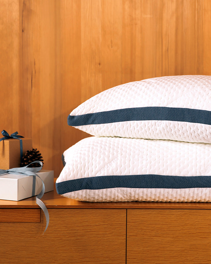 Stack of Custom Comfort Pillows sitting on a table next to a stack of wrapped presents.