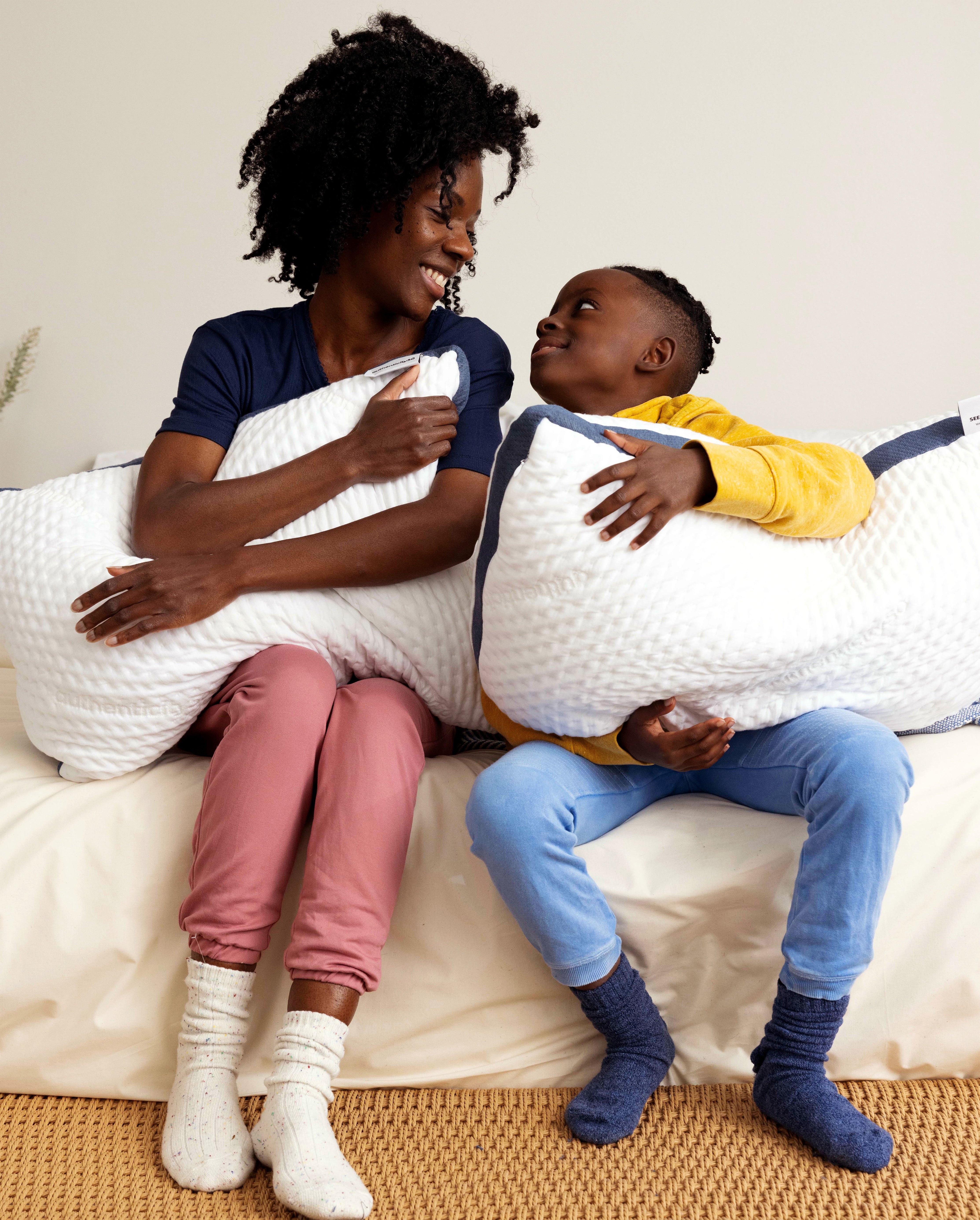 Mother and son sitting in bed smiling and hugging their Custom Comfort Pillows.