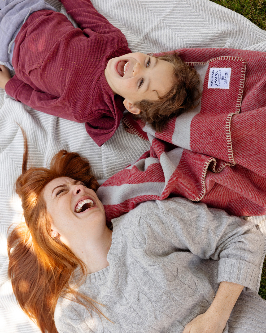 Mom and son lying on their Northwest Wool Throw and Heritage Blanket in their backyard.