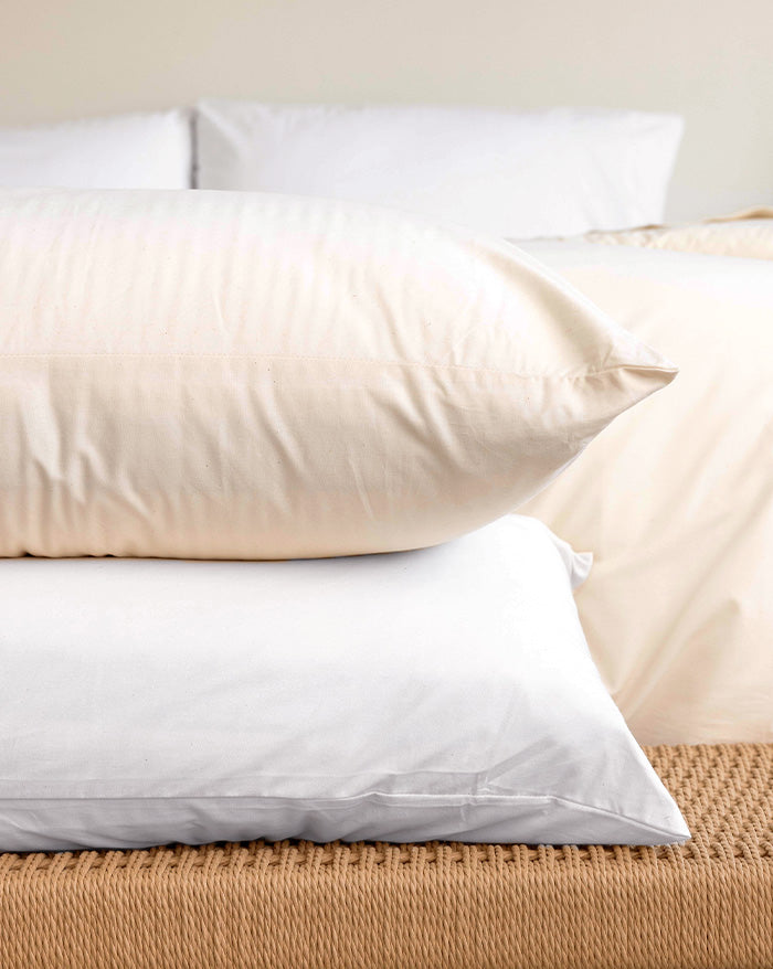 Two pillows stacked on top of each other, each dressed with an Envelope Closure Pillowcase (top in in Rustic Cotton and bottom in Cloud White).