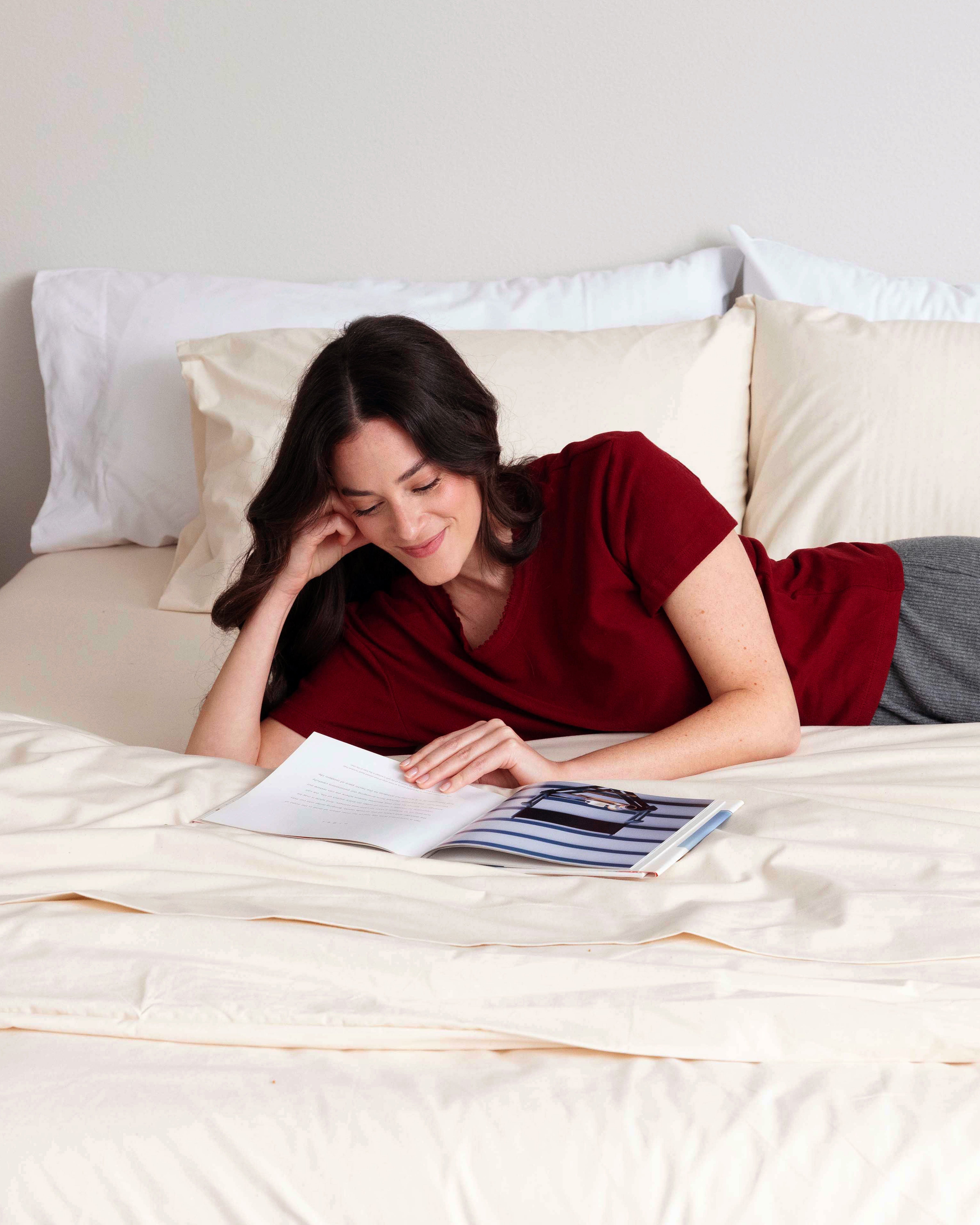 Woman laying in bed reading. The bed is made with a set of Rustic Cotton Heritage American Sheets.