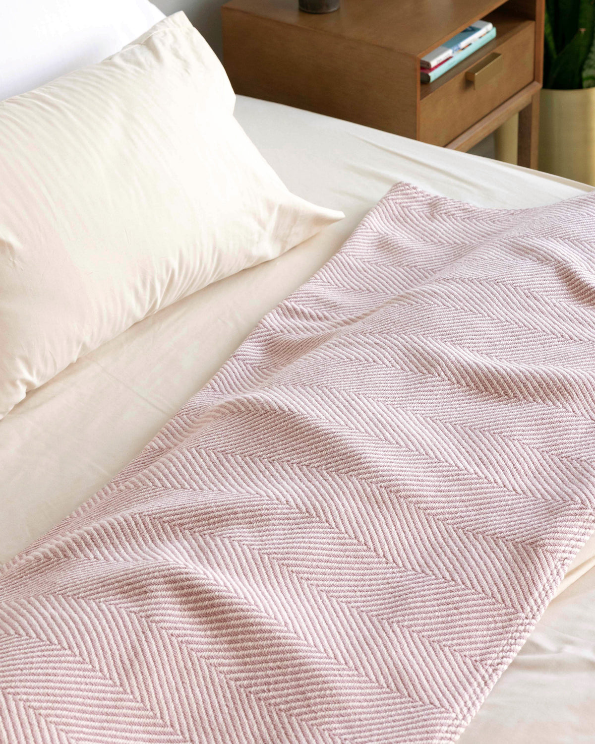 Desert Blush Heritage Blanket folded and laid out at the head of a bed.