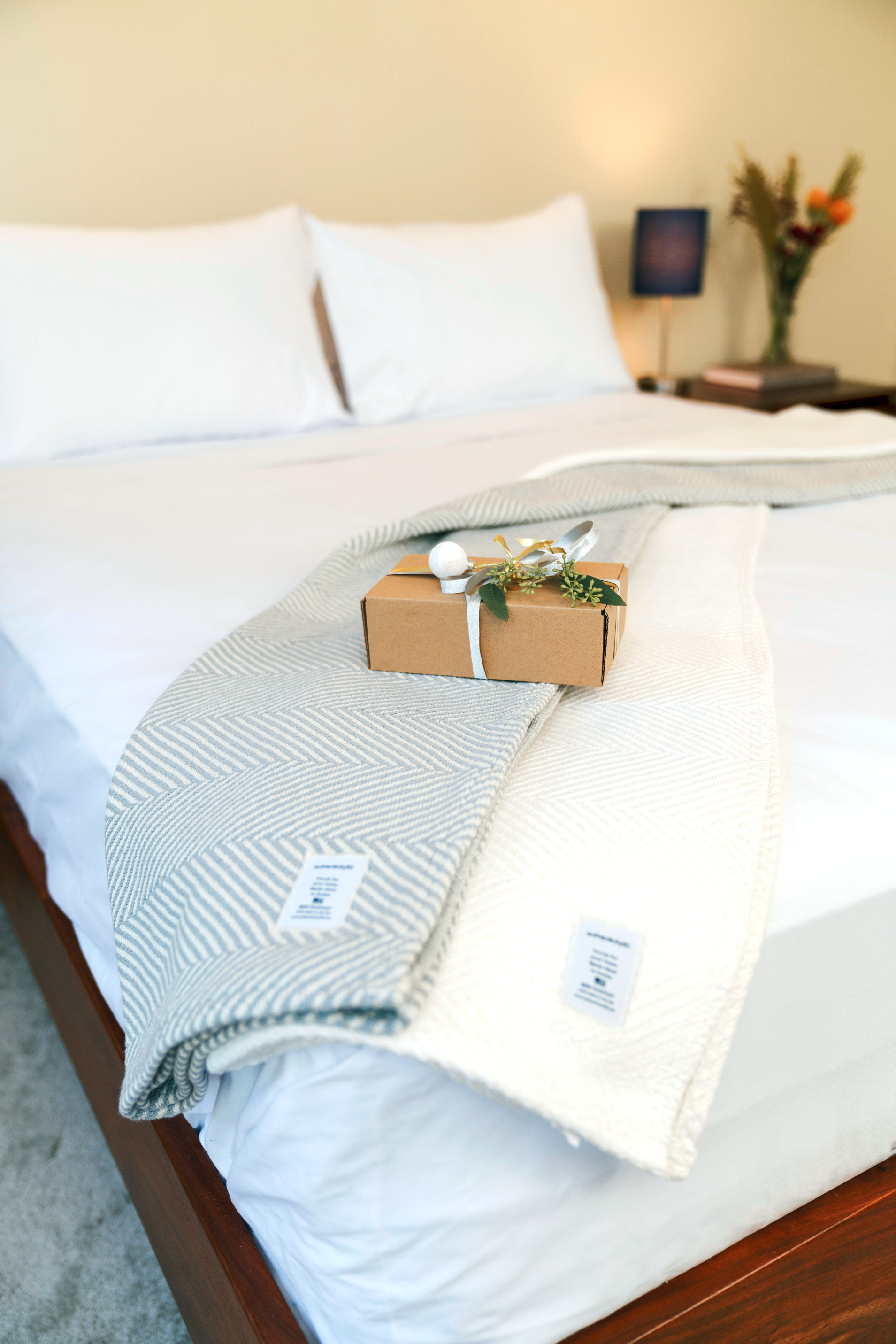 Wrapped gift sitting on top of two folded Heritage Blankets on the edge of a bed.