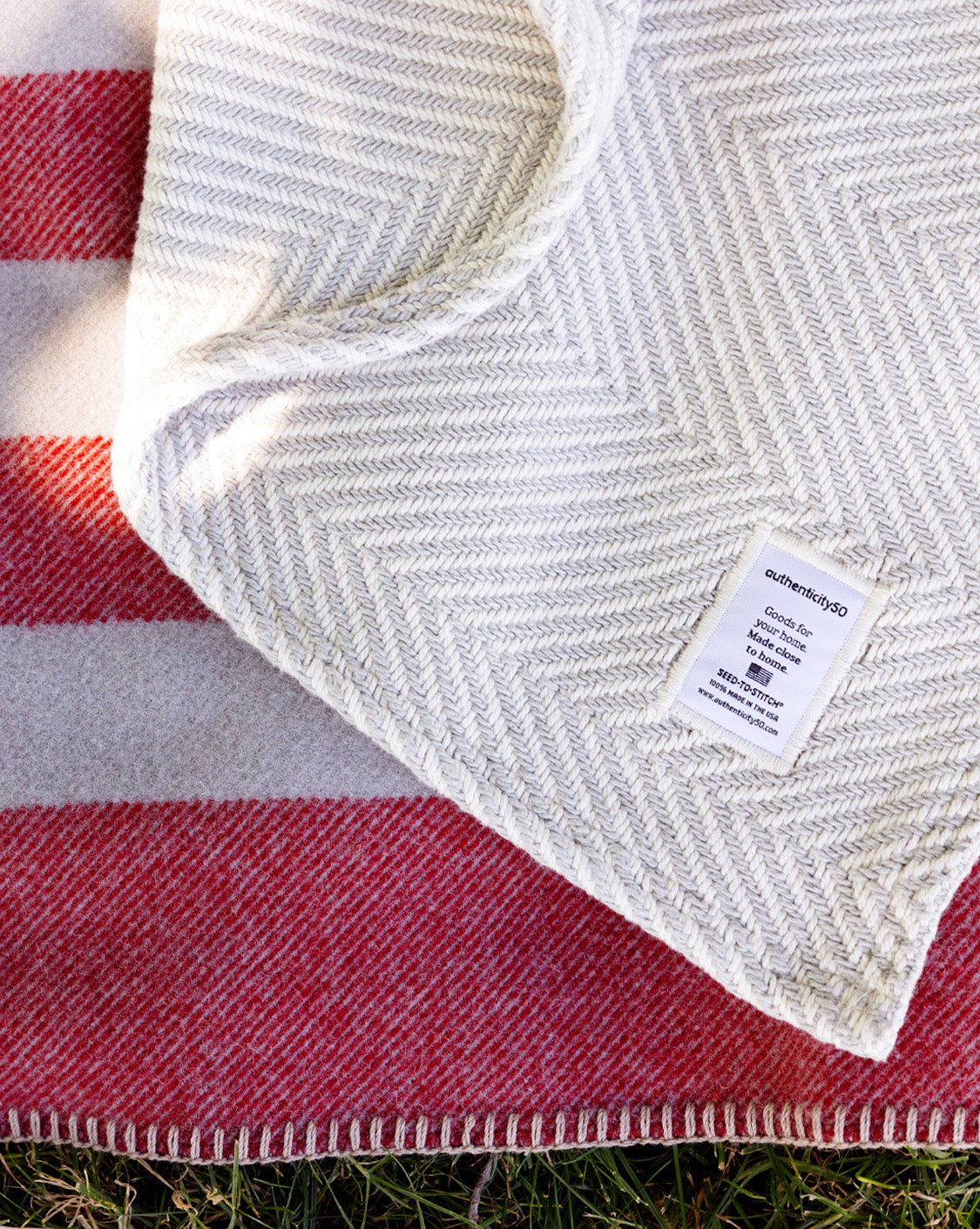 Northwest Wool Throw splayed out in a backyard with a Heritage Blanket lying over it.