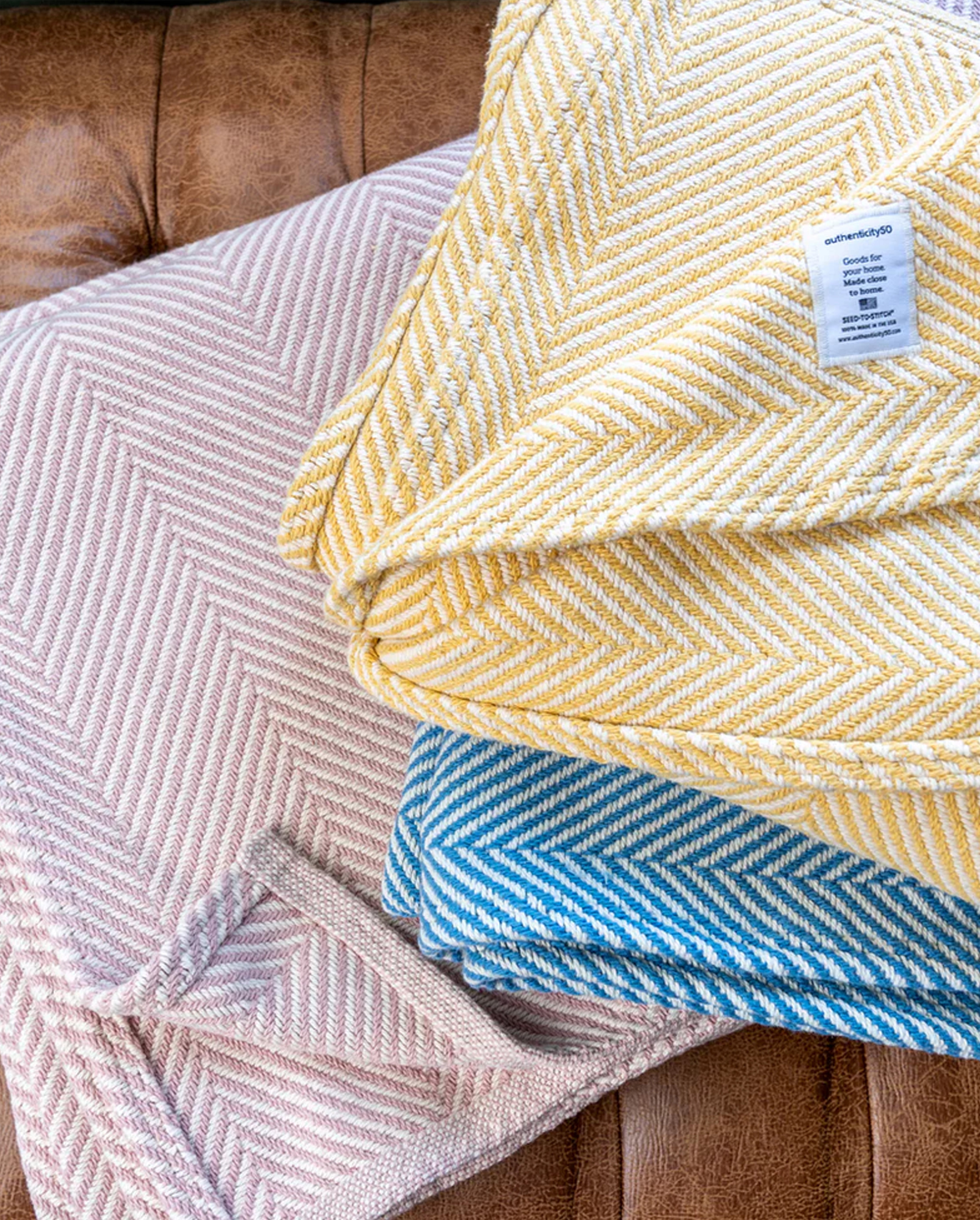Stack of folded Heritage Blankets in the colors Prairie Yellow, Coastal Blue, and Desert Blush.