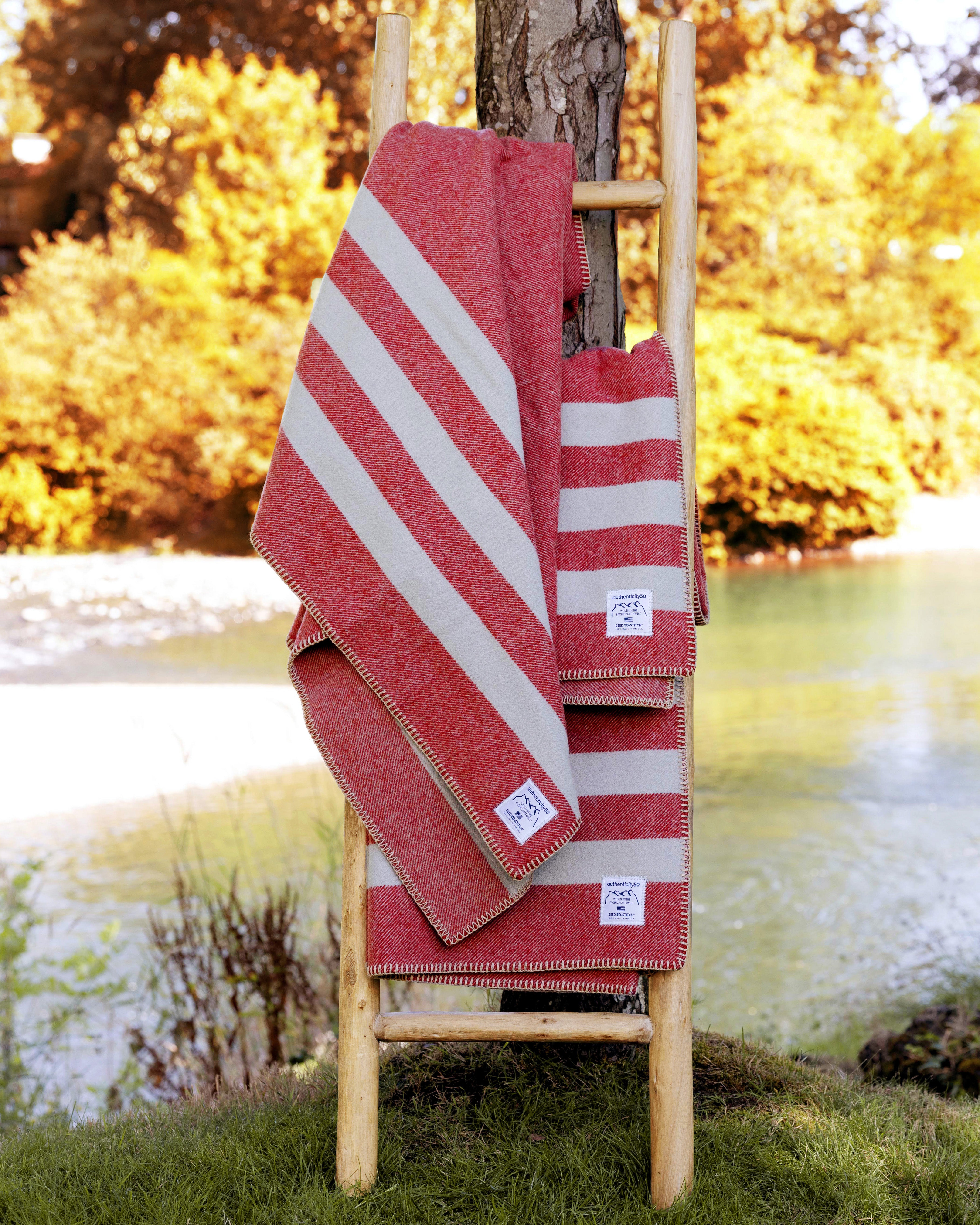 Three Northwest Wool Throws draped on a wood ladder leaning against a tree.
