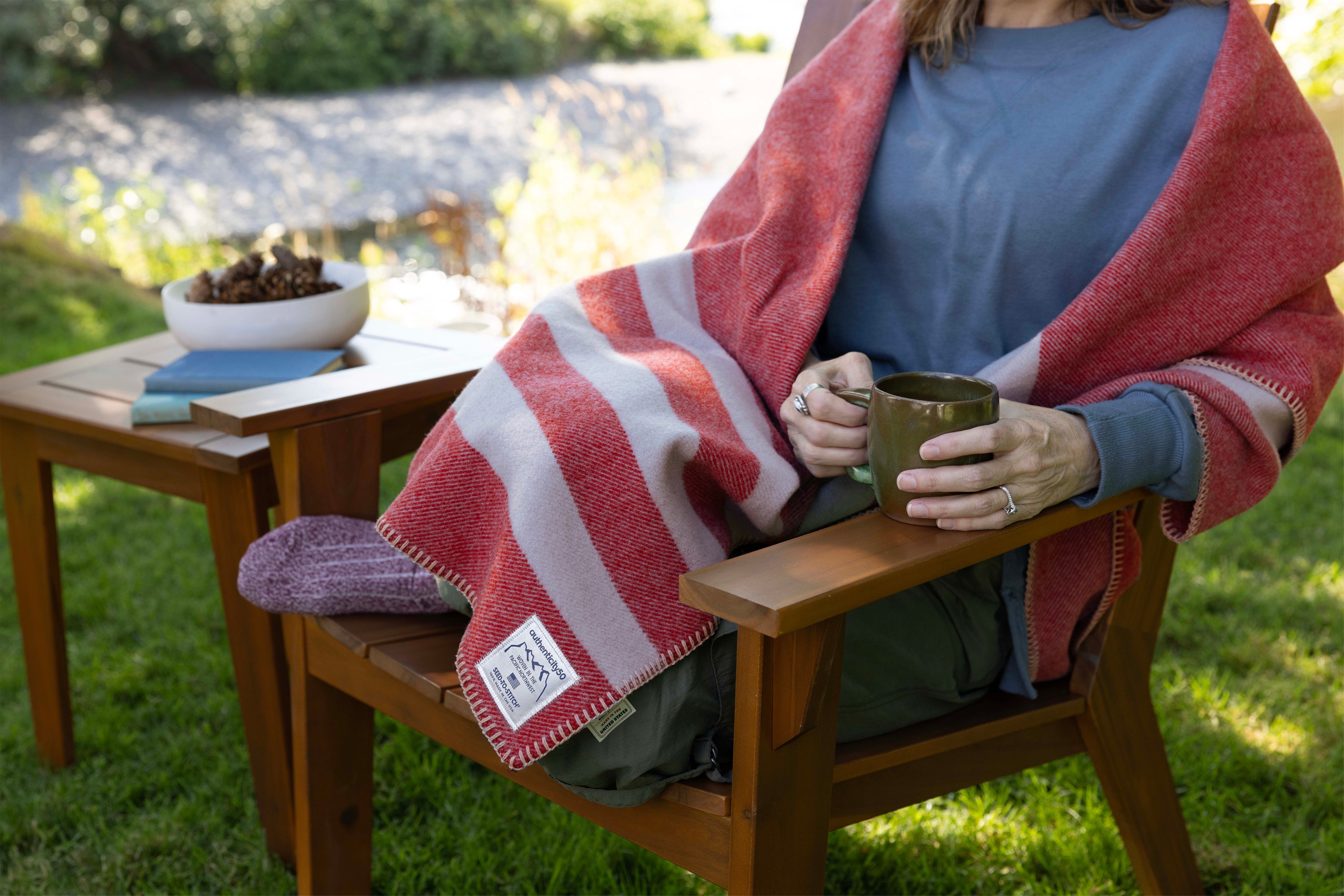 Woman relaxing outside with a mug of coffee and a Northwest Wool Throw.