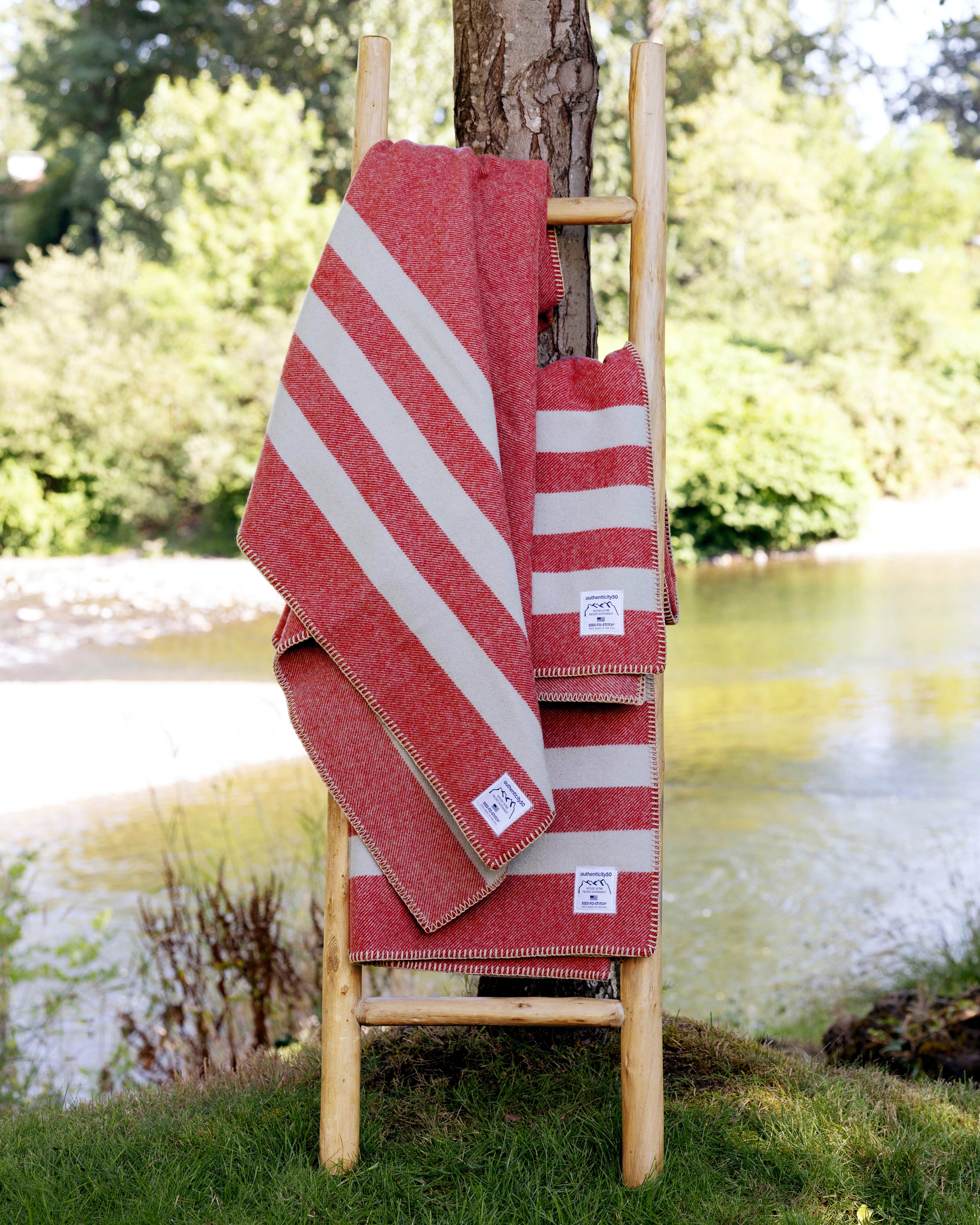 Three Northwest Wool Throws draped on a wood ladder leaning against a tree.