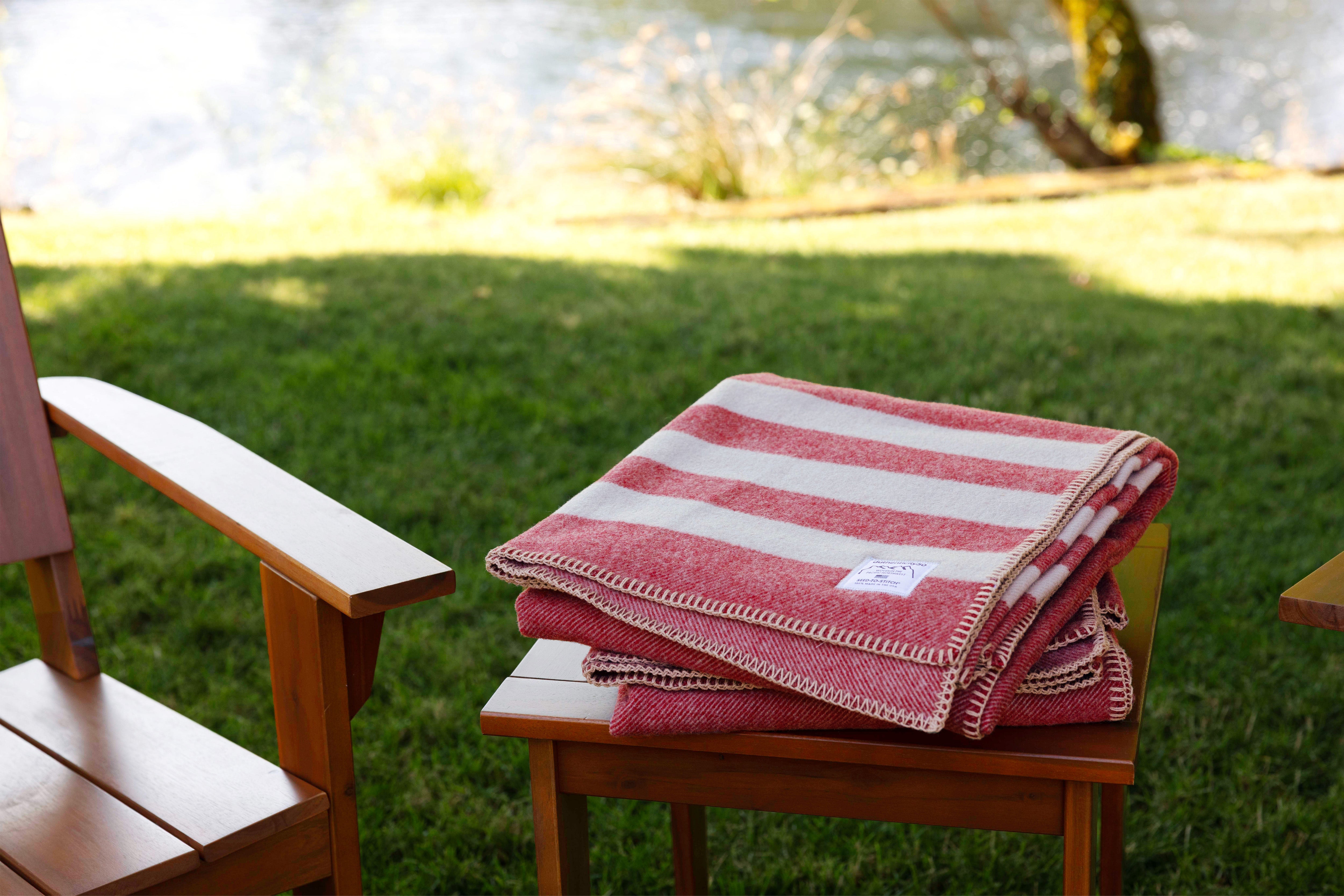 Folded stack of Northwest Wool Throws on a outside table chair set.