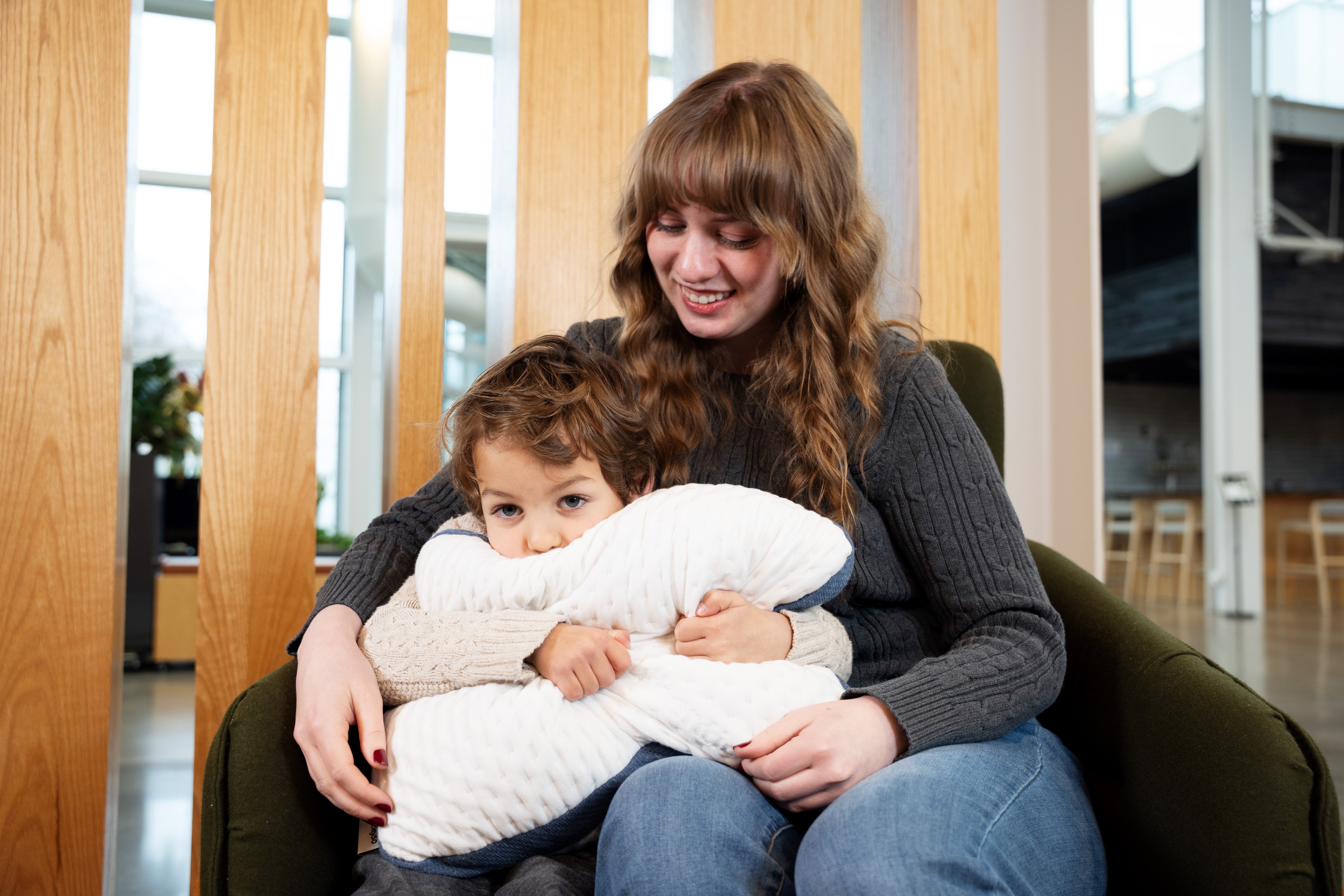 Mother and son sitting in a chair snuggling an A50 Travel Pillow.