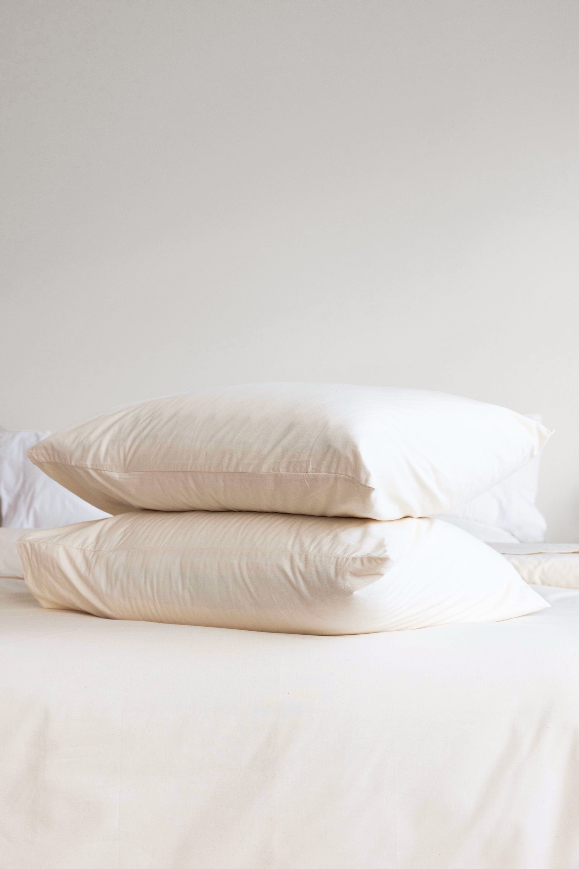 Stack of pillows on a bed. The pillows have Rustic Cotton Envelope Closure Pillowcases on them.