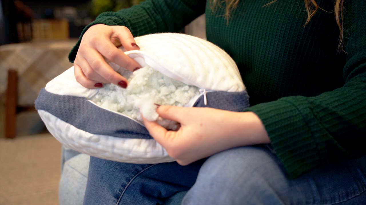 Woman pulling foam out of an unzipped A50 Travel Pillow.