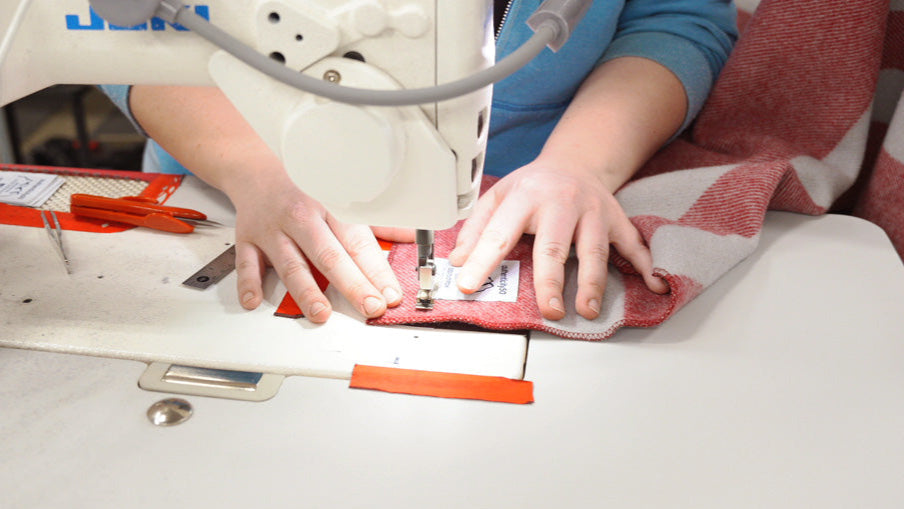 Sewing the "Woven in Washington" tag on the corner of a Northwest Wool Throw.