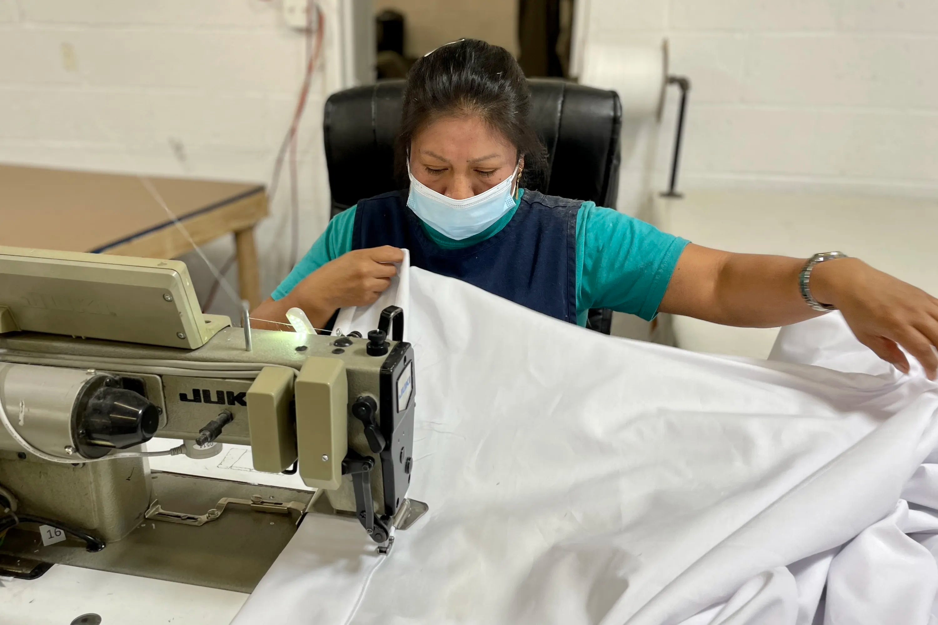 Person hand sewing Signature Sheets.