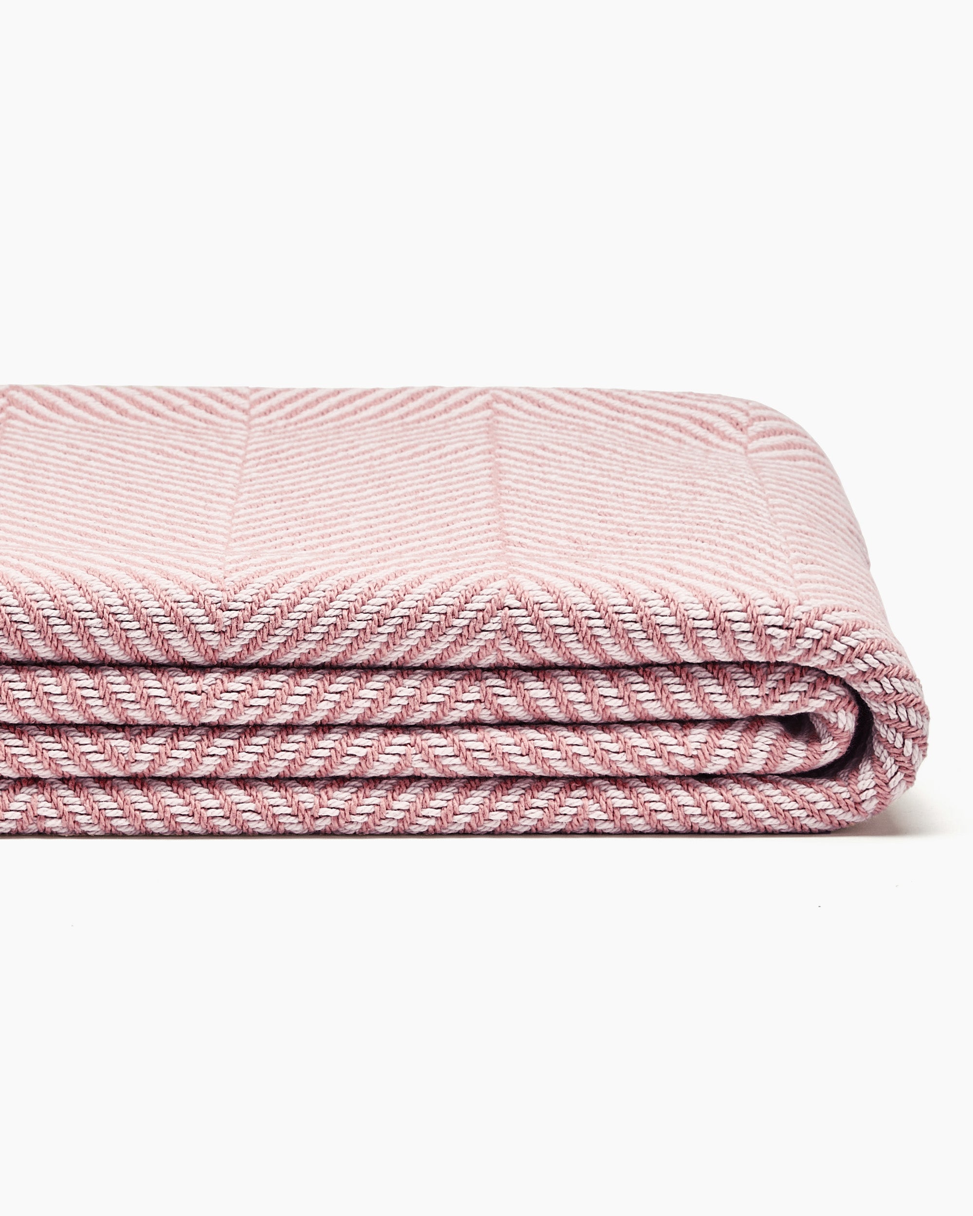 Stack of folded striped blankets in beige, yellow, and blue, displaying a wide herringbone pattern.