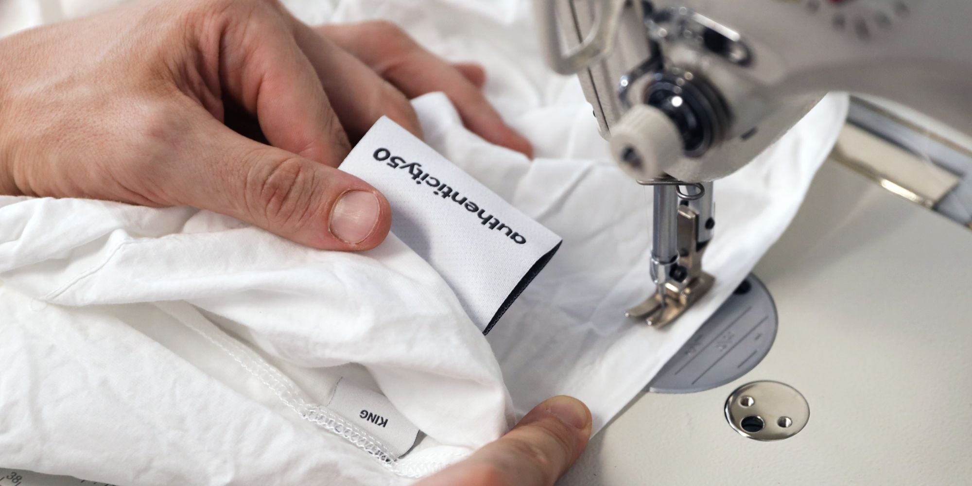 sewing the authenticity50 label onto sheets