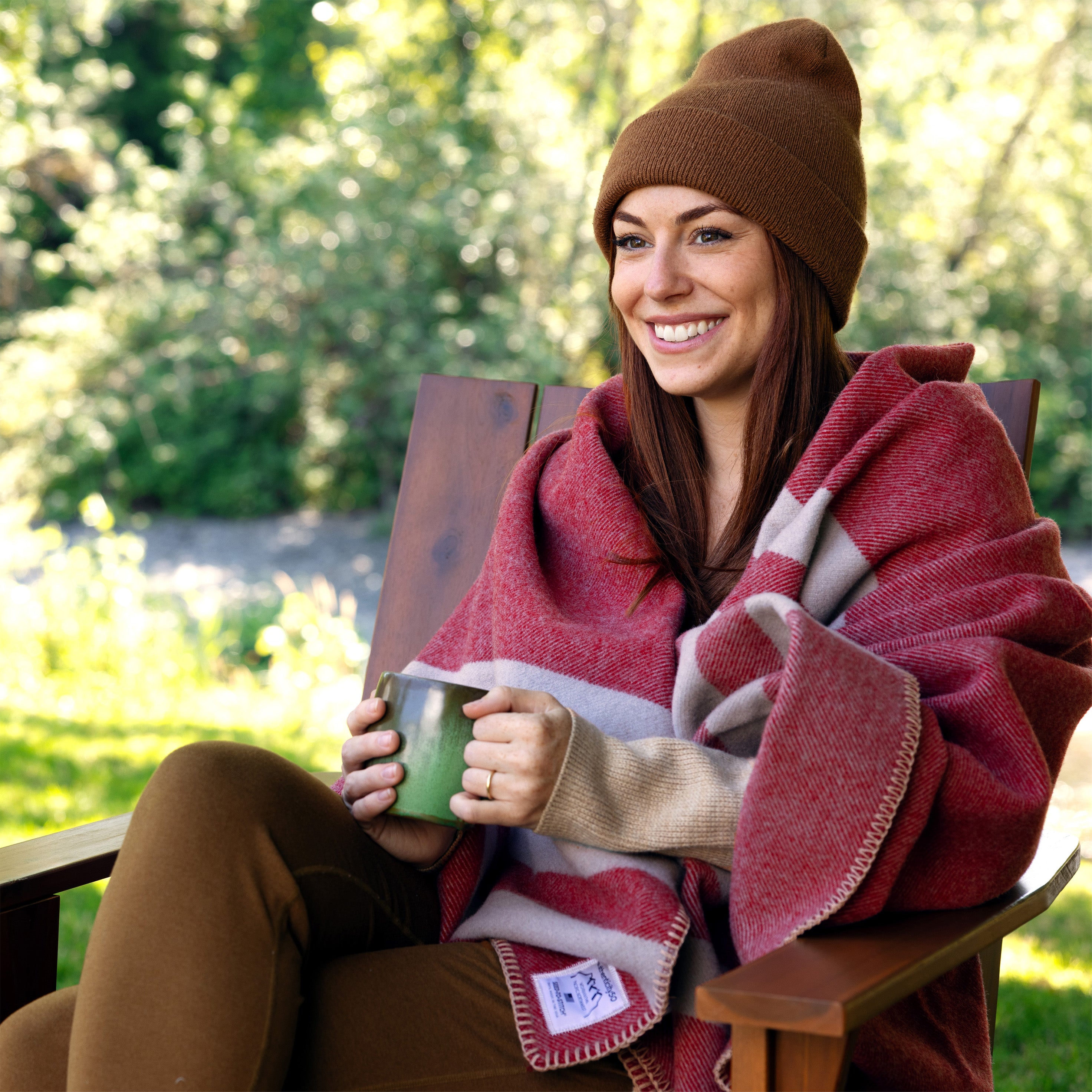 Woman enjoying a cup of coffee in her backyard wrapped in a Northwest Wool Throw.