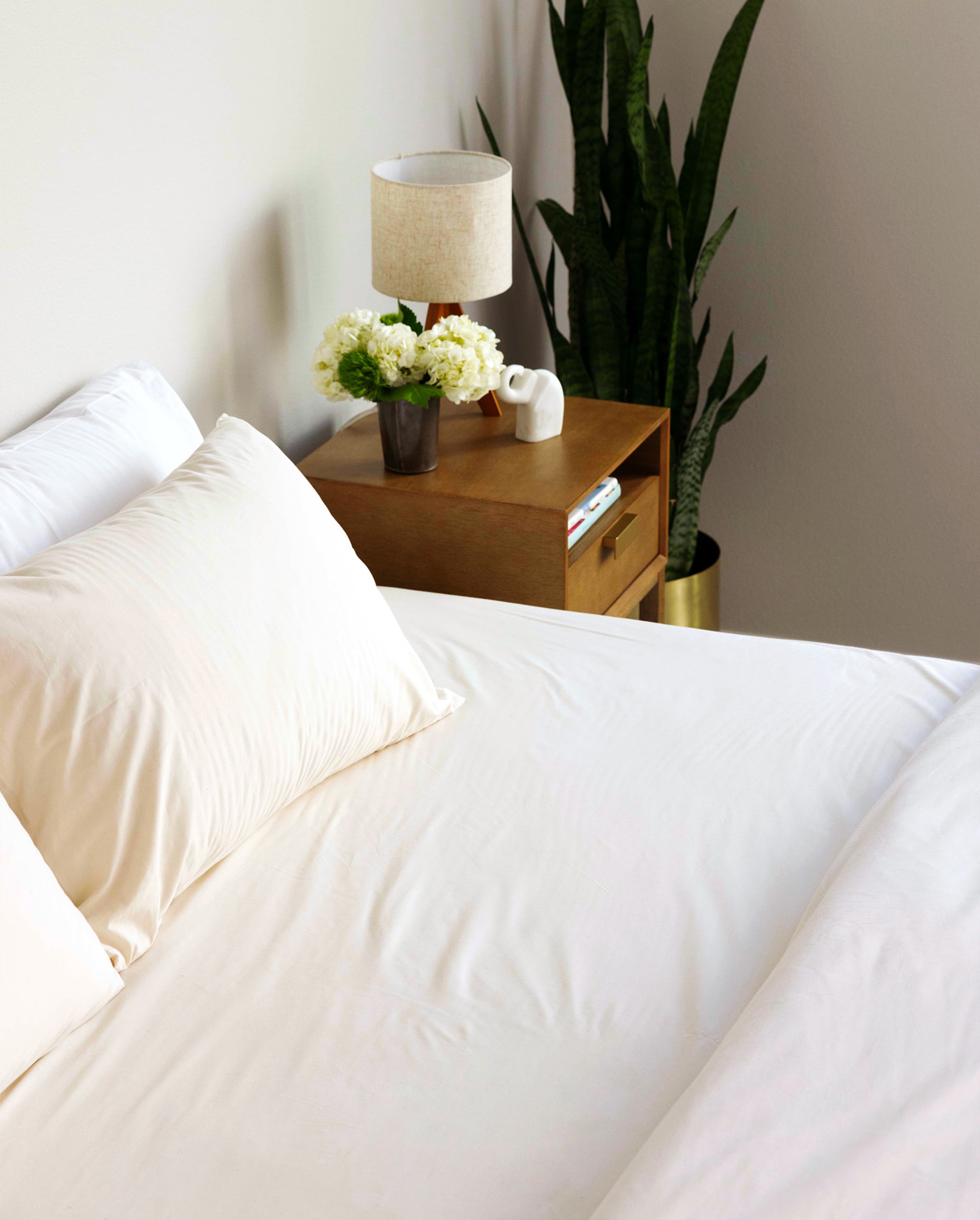 Bed made with A50 bedding, with the duvet pulled back to show off the Rustic Cotton A50 Fitted Sheet.
