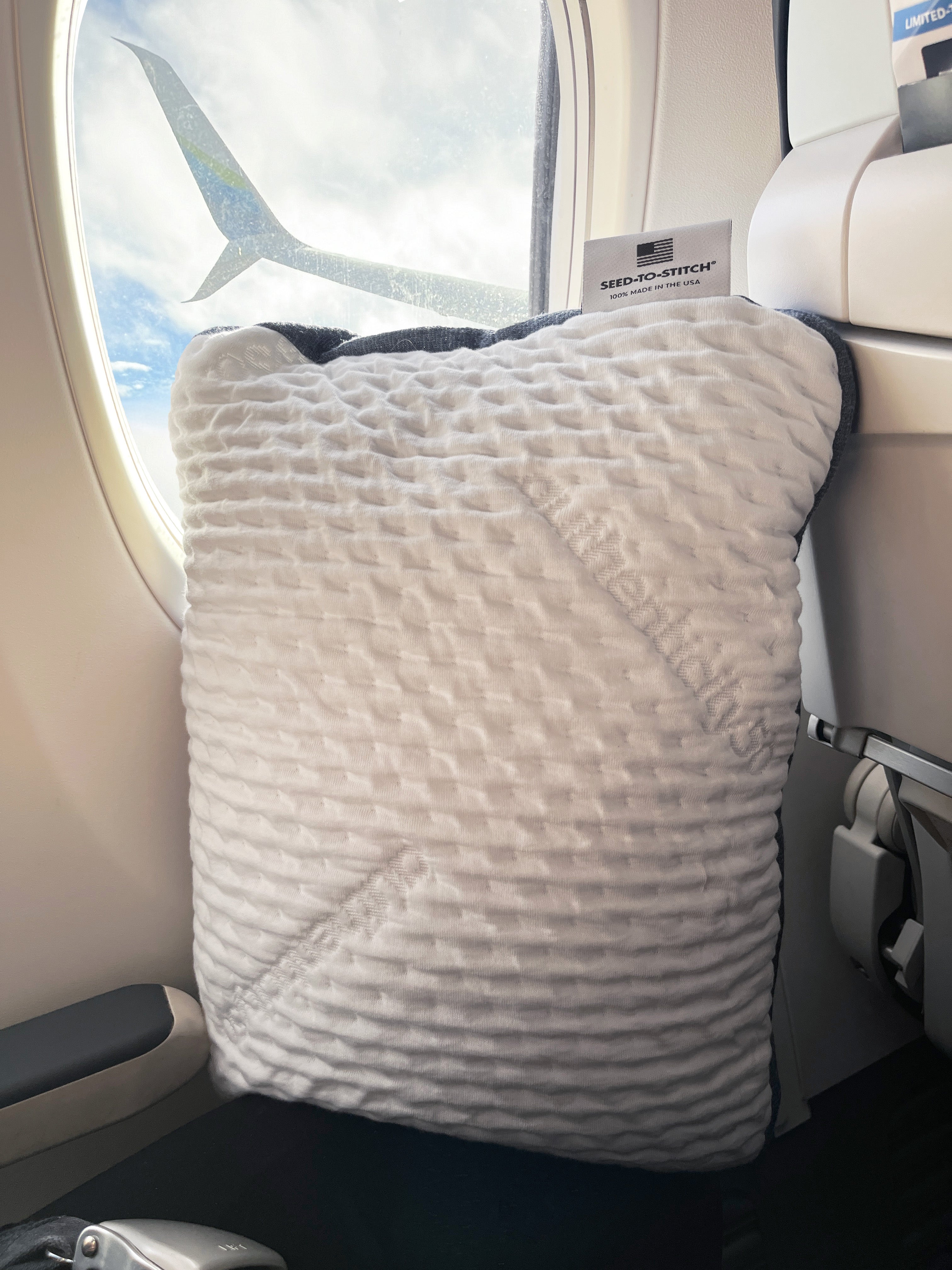 A50 Travel Pillow propped up against the window of a plane as it takes off.