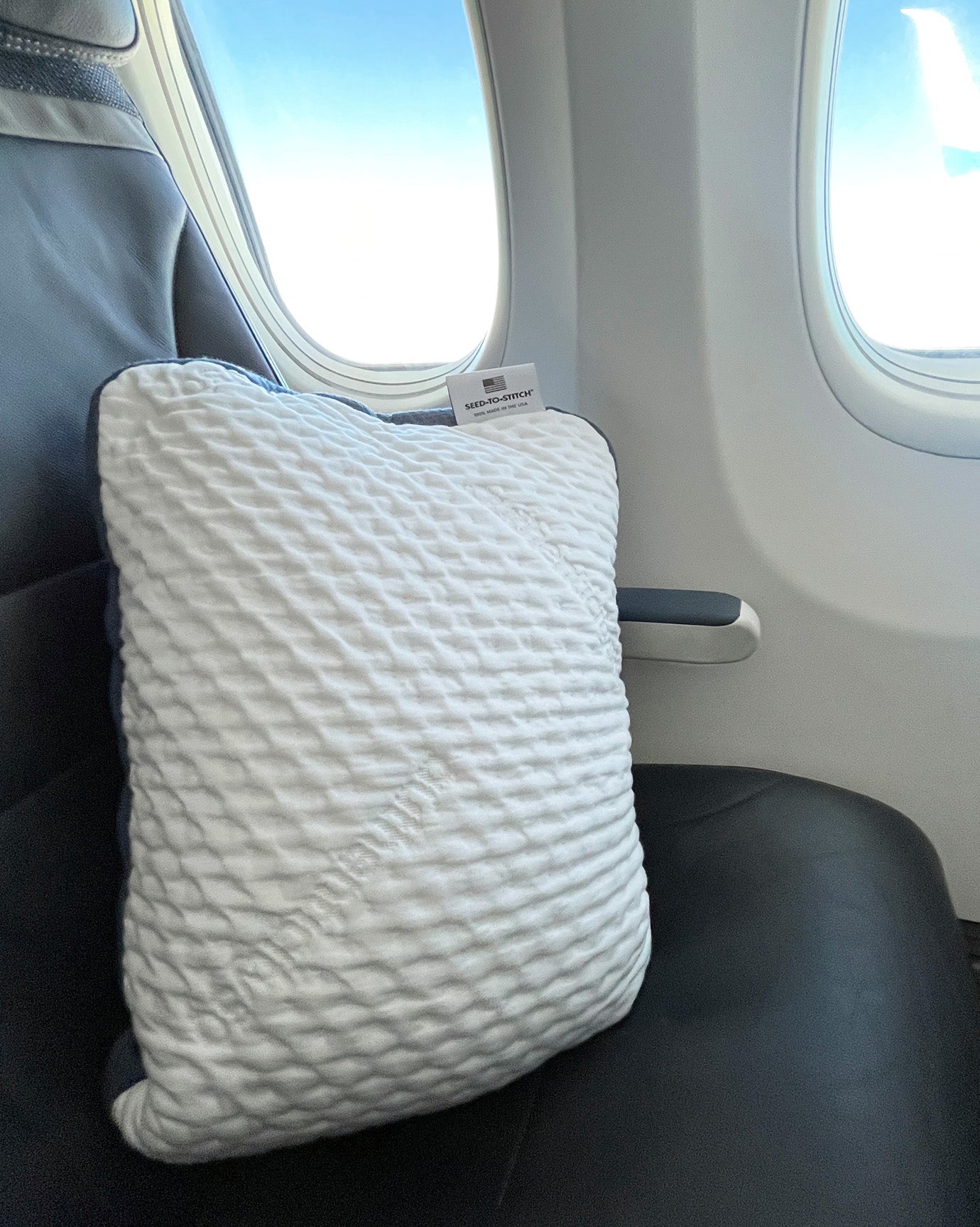 A50 Travel Pillow propped up in a seat on an airplane.