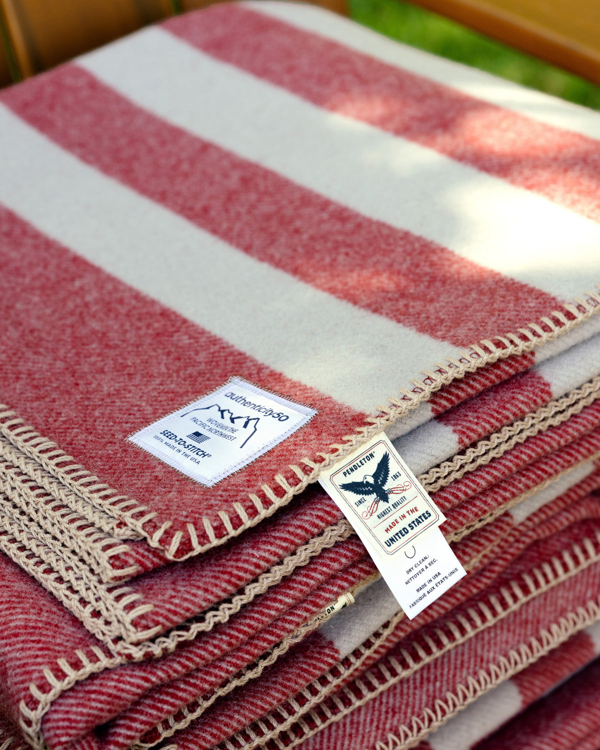 Northwest Wool Throw folded and sitting on a chair. The custom Authenticity50 label and Pendleton Woolen Mills® tags are on display.