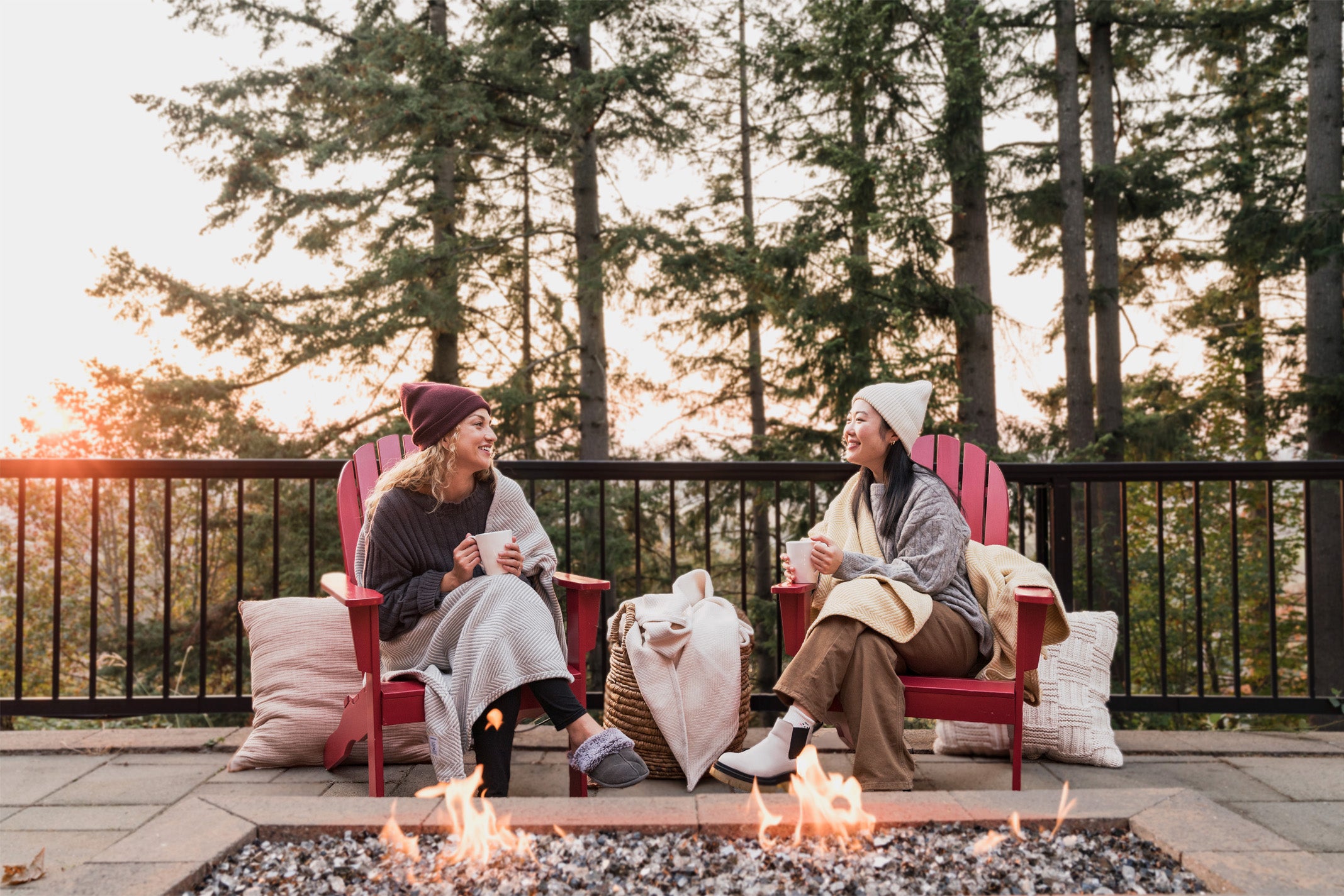 Two women enjoying an evening on the back deck wrapped in Heritage Blankets.