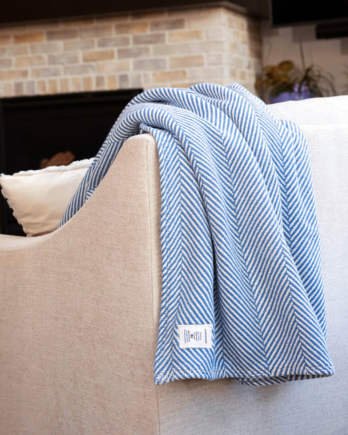 A Coastal Blue Heritage Blanket draped over the back of a couch.