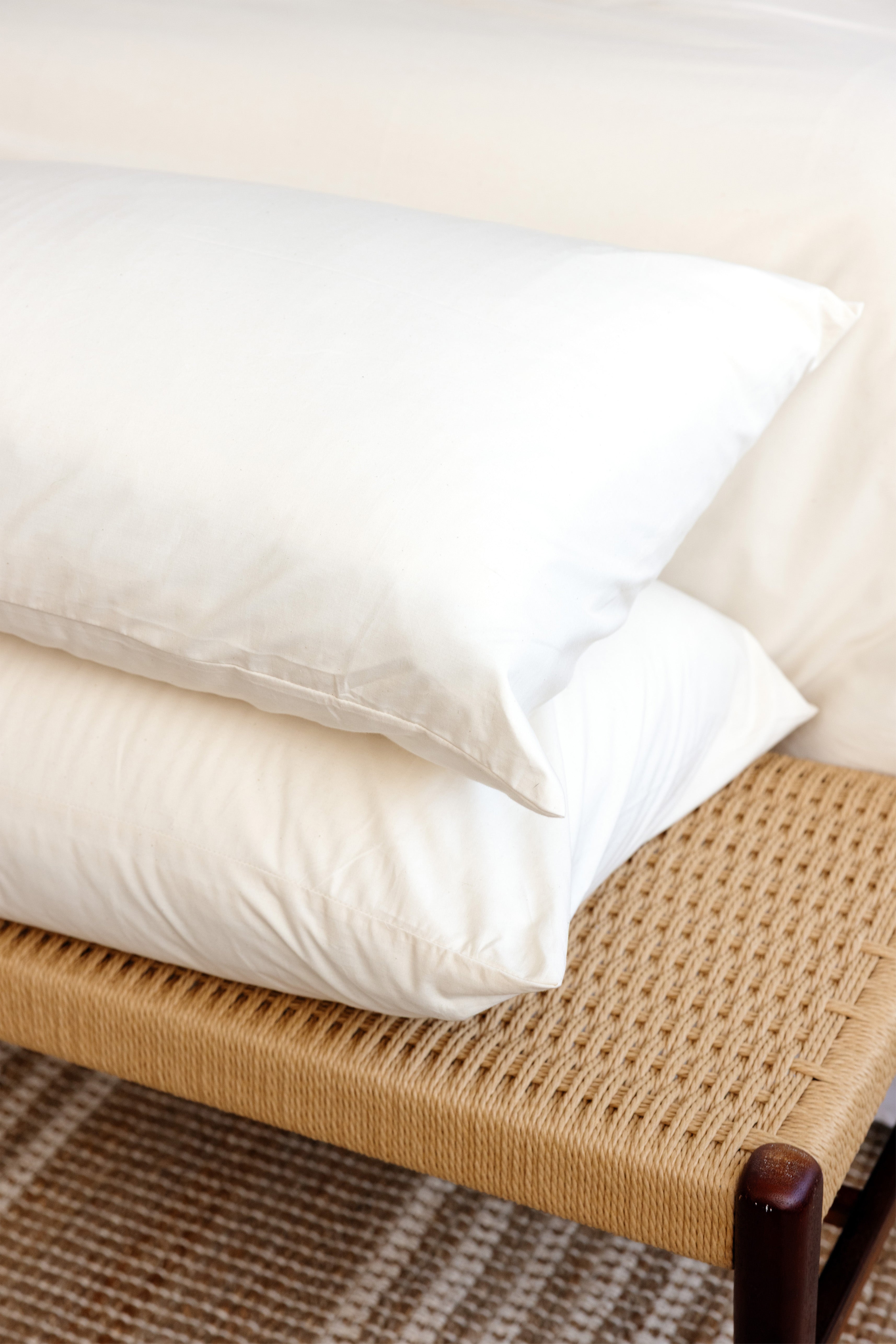 Two Custom Comfort Pillows in Envelope Closure Pillowcases stacked at the foot of a bed.