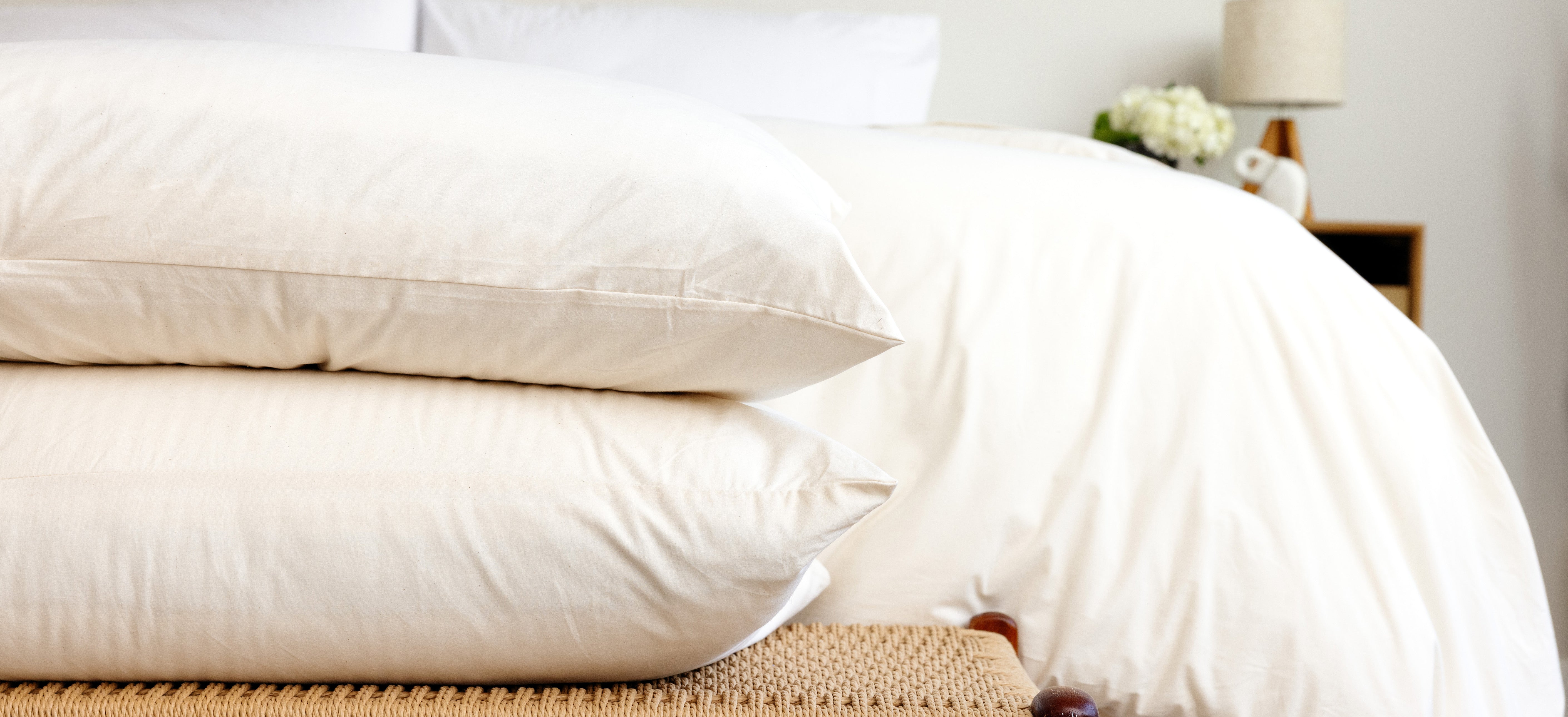 Two Custom Comfort Pillows tucked in Rustic Cotton Envelope Closure Pillowcases stacked neatly at the foot of a bed.