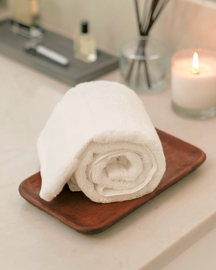 Rolled up Essential Cotton washcloth sitting on a bathroom counter.