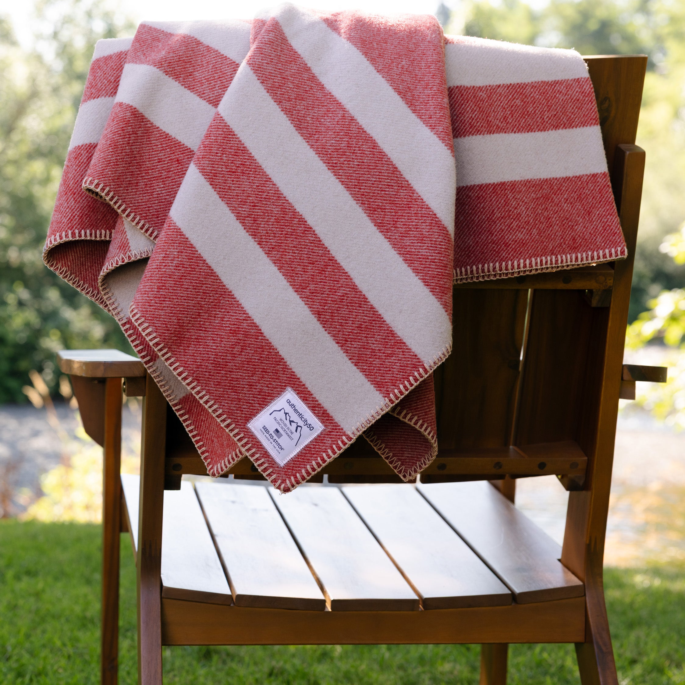 Folded Northwest Wool Throw draped on the back of a chair in a backyard.