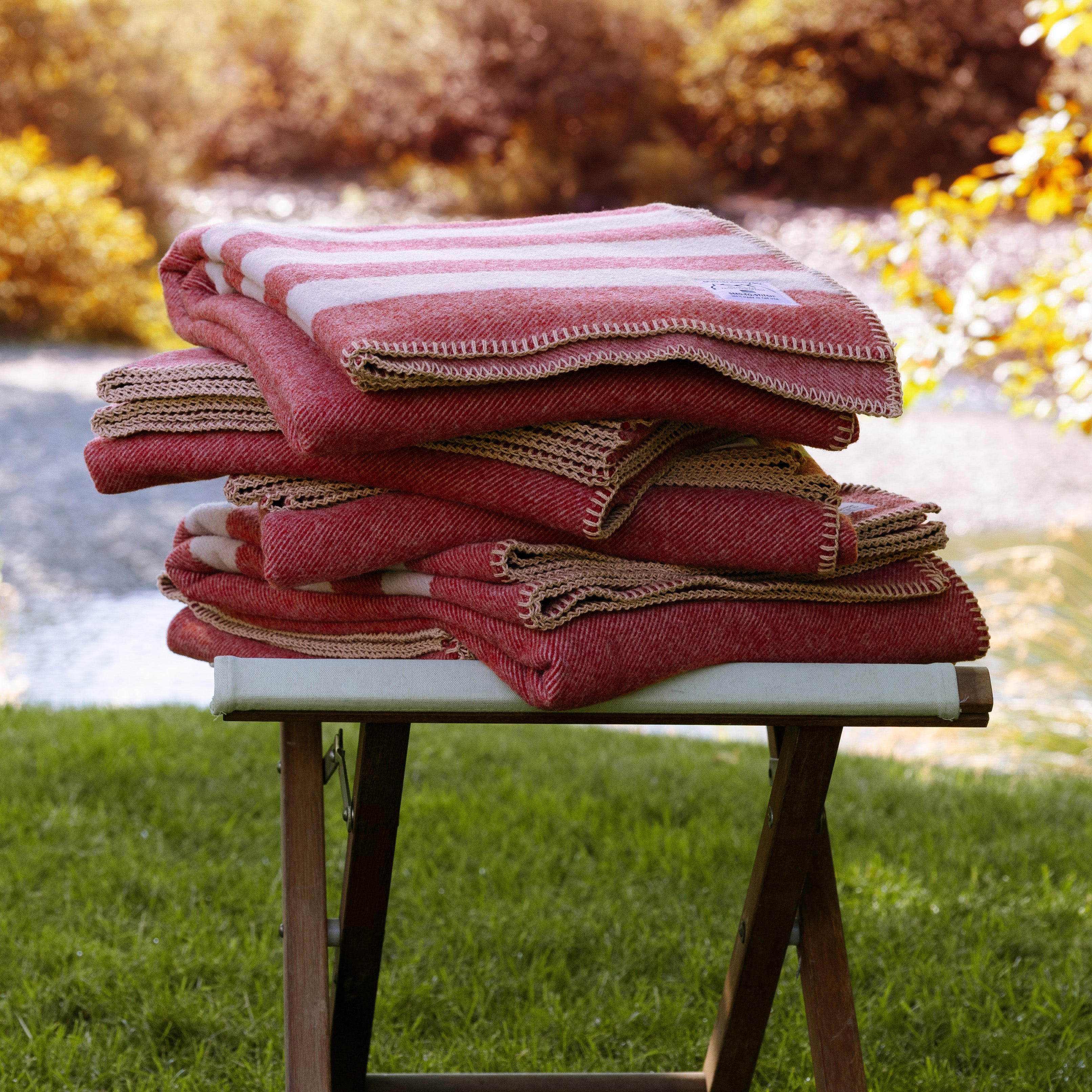 Stack of folded Northwest Wool Throws on a footrest in a backyard.