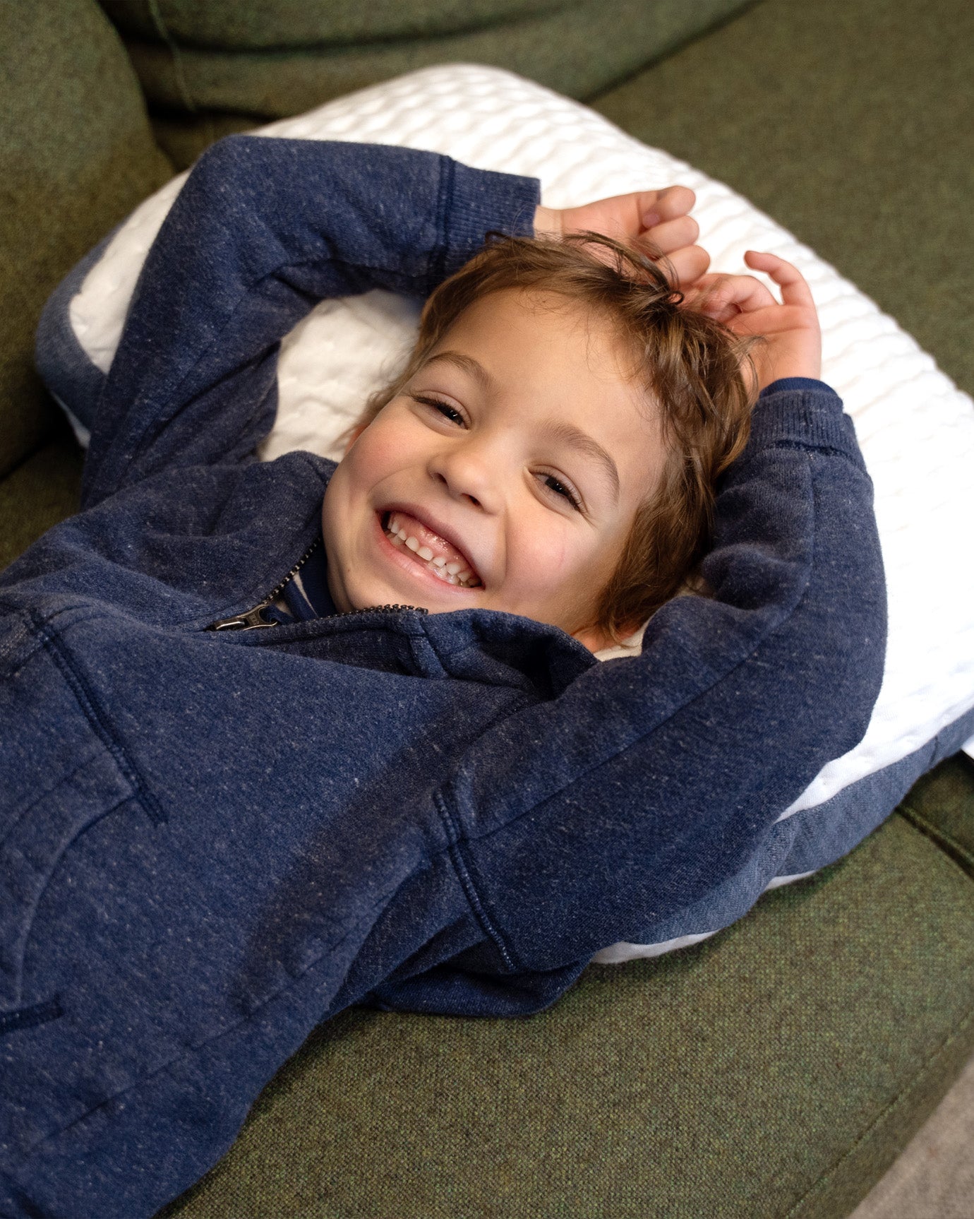 Kid laying back on his A50 Travel Pillow and smiling.
