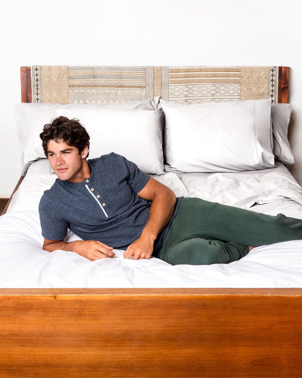 Man laying on his bed, which is dressed in Cloud White Heritage American Sheets and a Signature White A50 Duvet Cover.