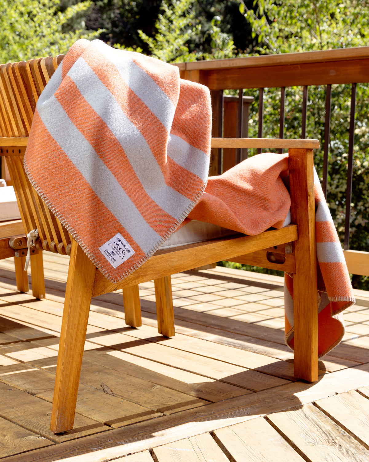 Mesa Sunset Northwest Wool Throw draped over the back of a chair on a back deck.