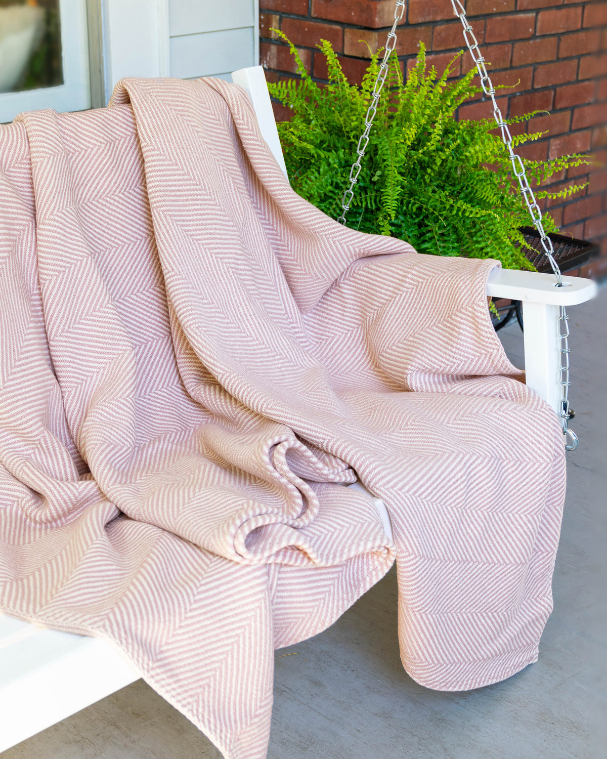 Desert Blush Heritage Blanket unfolded and draped over a porch swing.