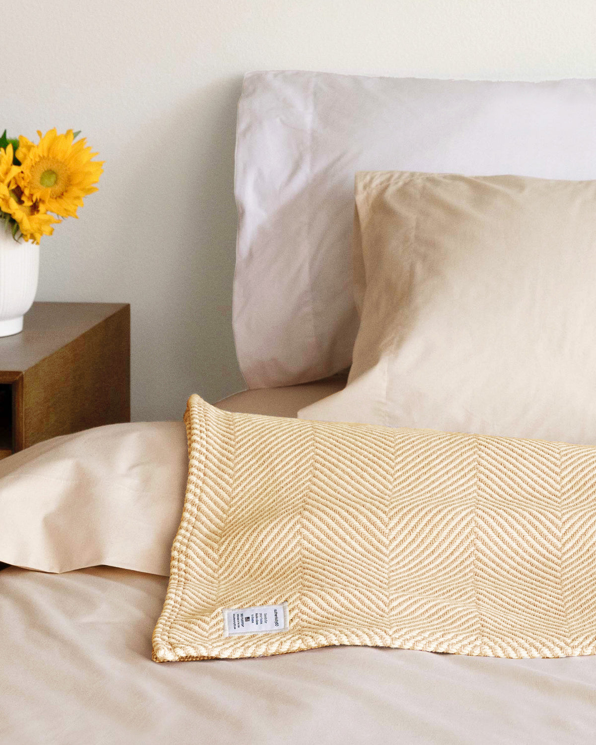 Prairie Yellow Heritage Blanket lying at the top of a bed.