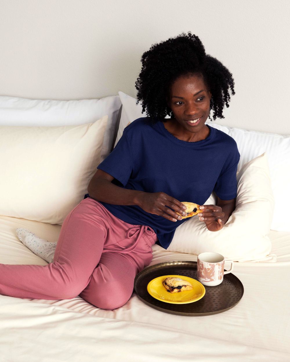 Woman sitting in bed, which is dressed with Rustic Cotton Heritage American Sheets.