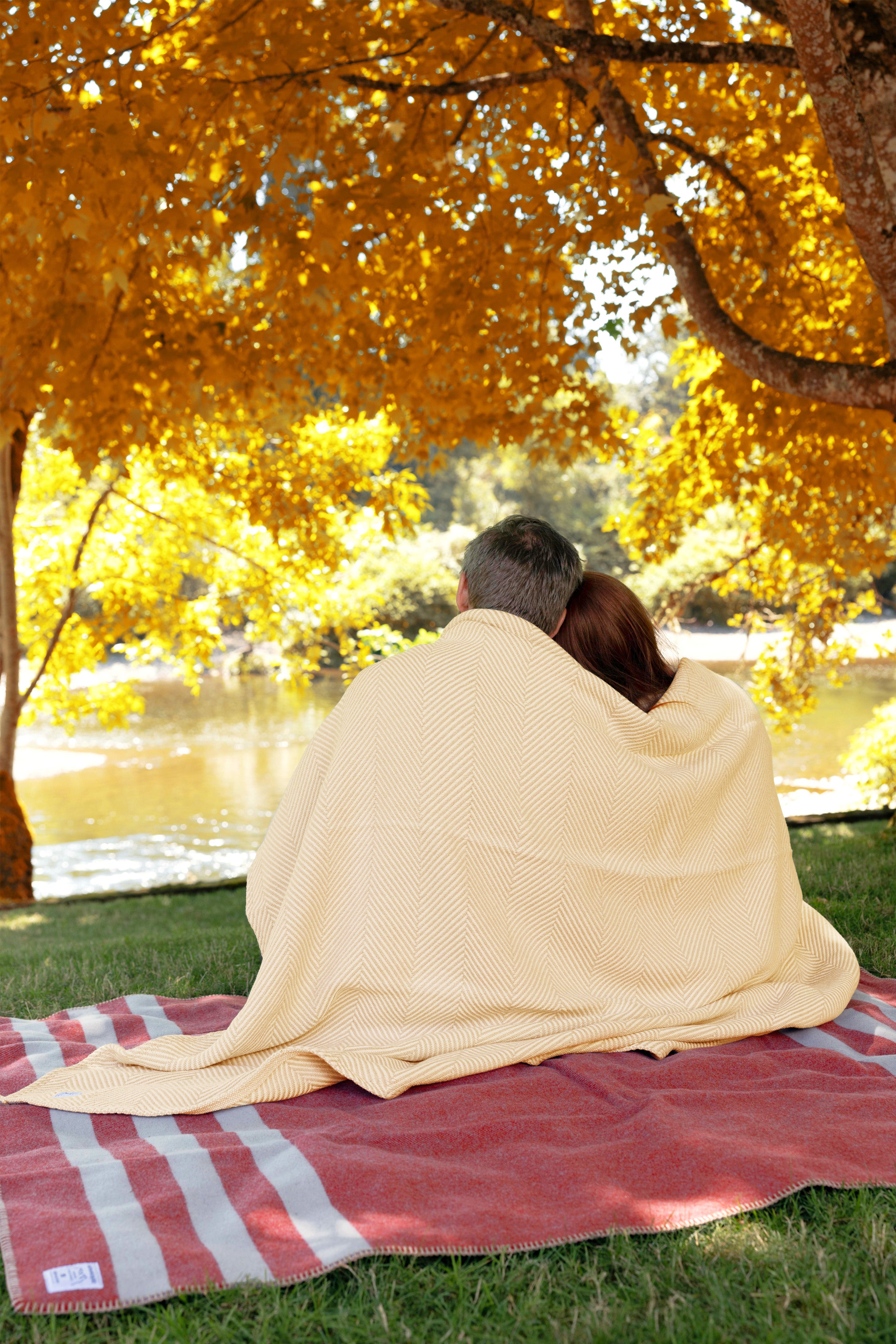 Husband and wife relaxing in their backyard wrapped in a Heritage Blanket and sitting on a Northwest Wool Throw.
