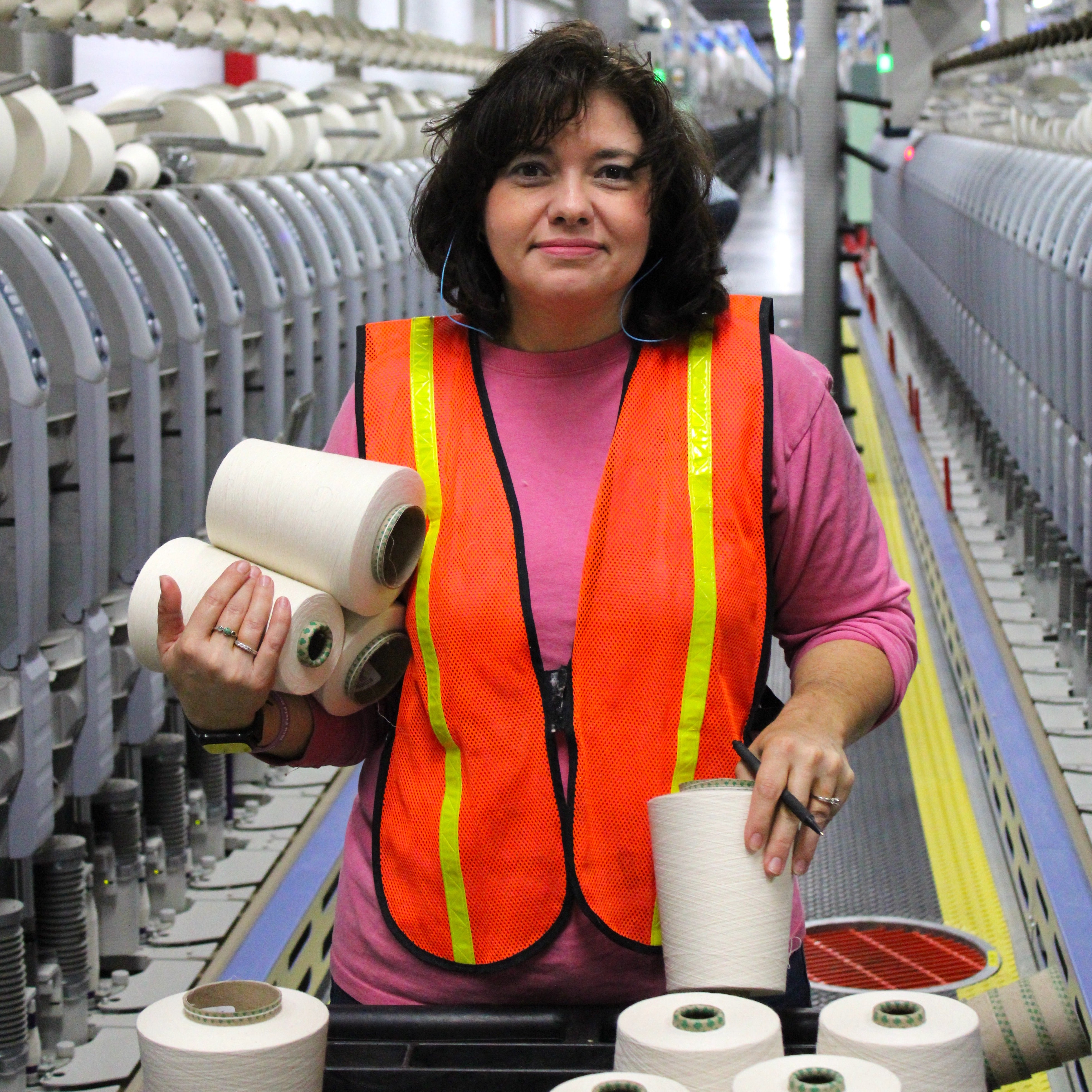 american worker holding cones of cotton yarn