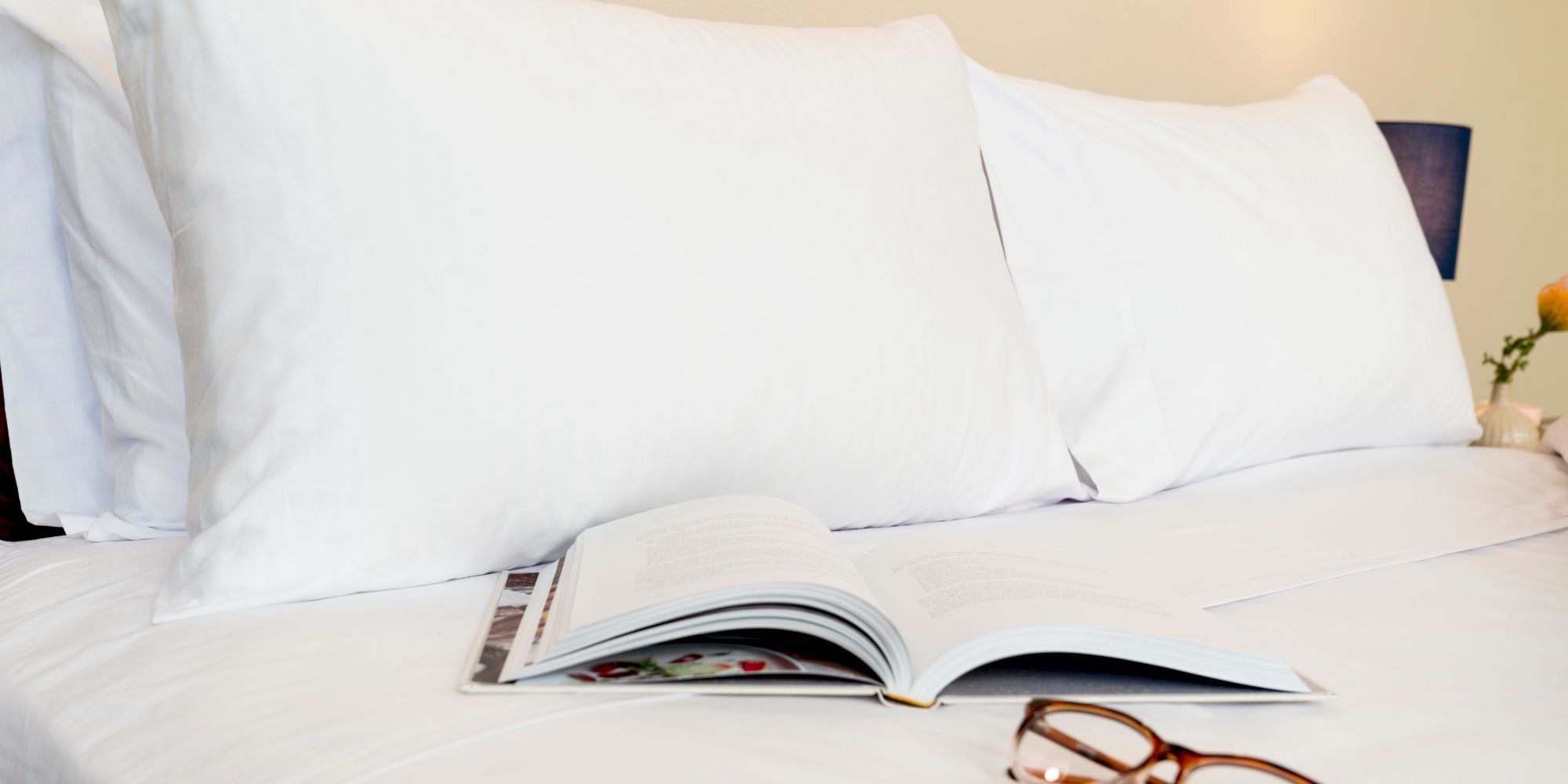 nice white pillowcases on a nice bed with a book and glasses