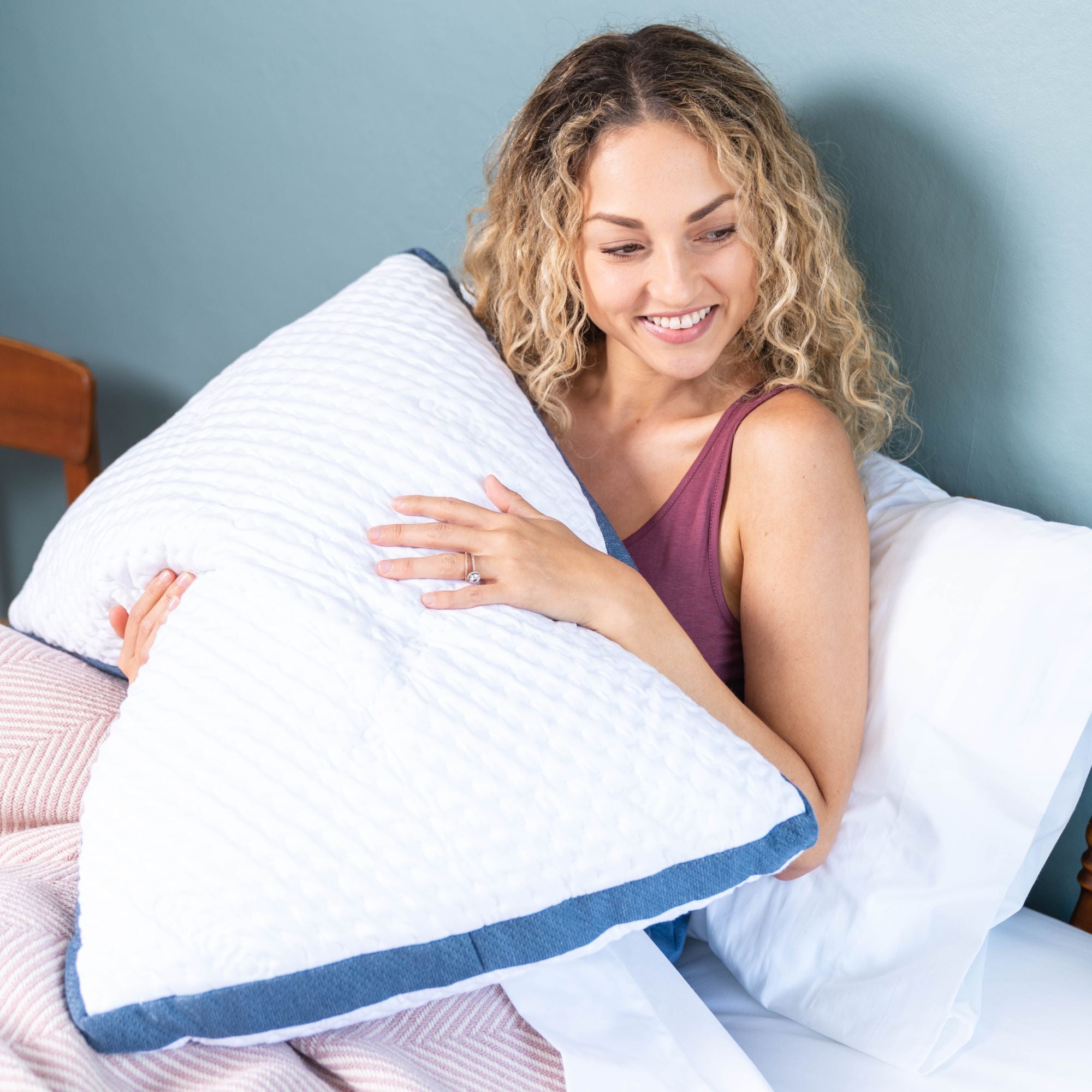 lady holding a foam core pillow in bed