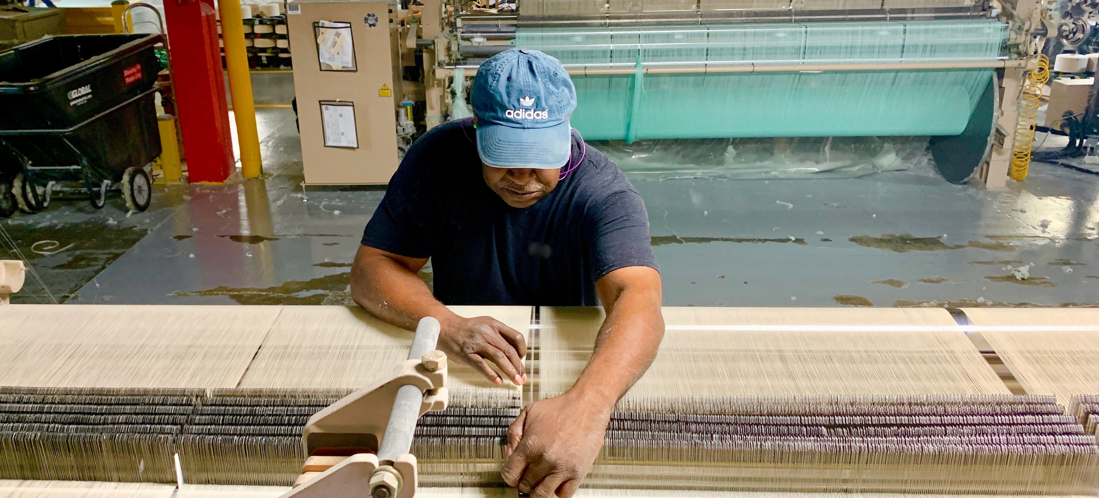 man working on american looms to weave fabric 