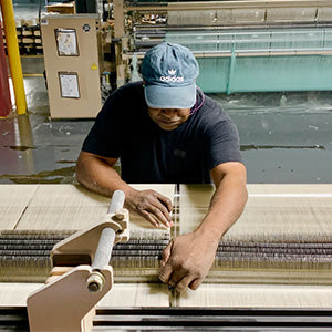 Man weaving fabric on looms in America.